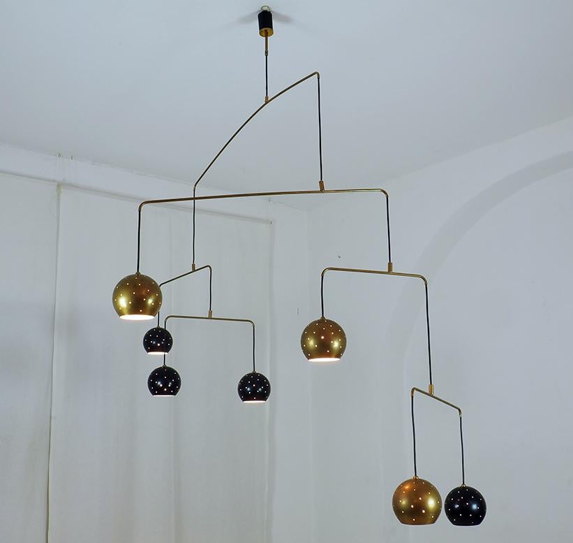 Original Italian brass mobile chandelier manufactured in a very small handcraft production in Milano, 20th century
Large, magic and poetical mobile chandelier with brass and black suspending spheres, it can moves with the flow of air.
Wholly in