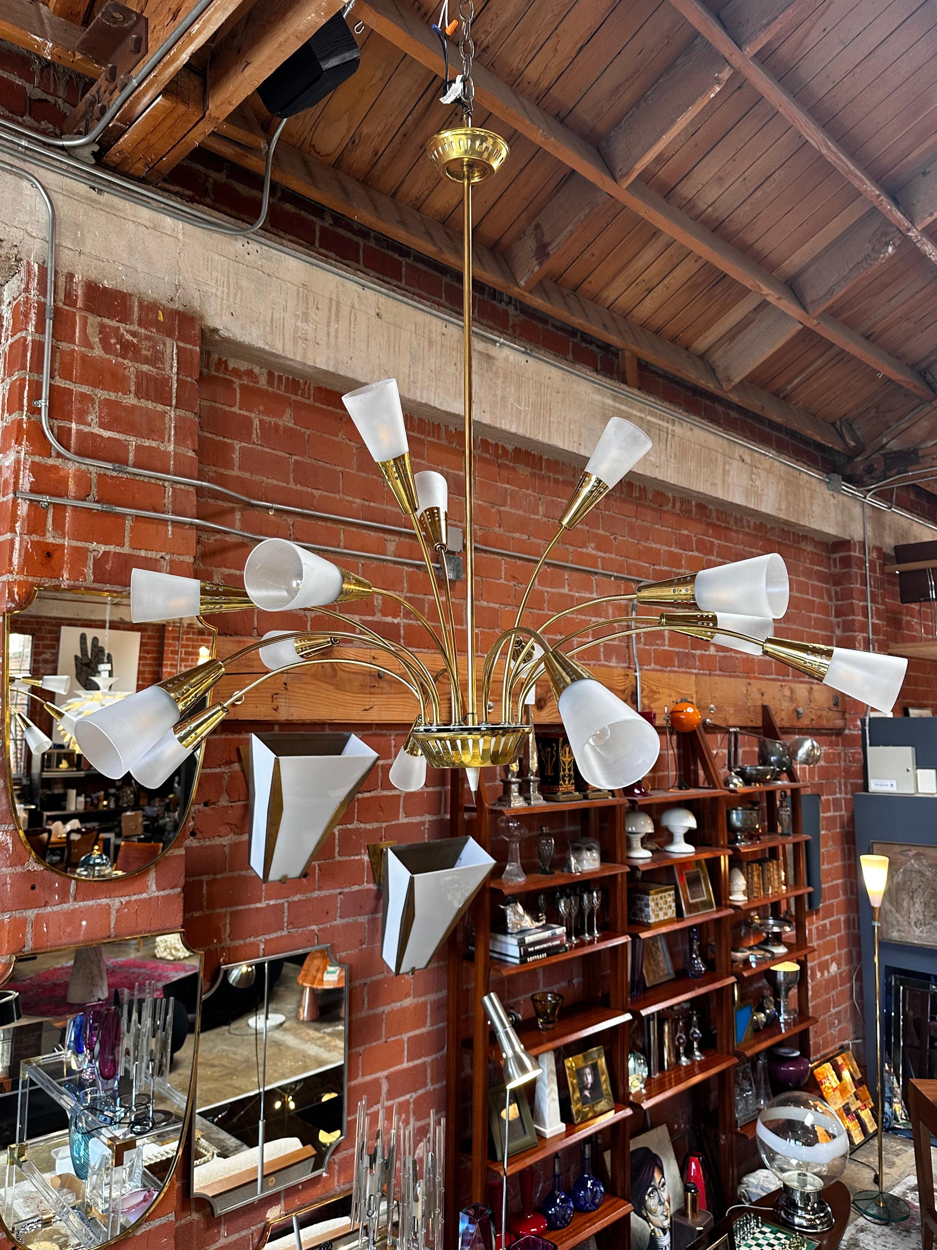 The Mid Century Italian Brass Cascade Chandelier from the 1960s is a stunning piece, boasting 15 brass arms adorned with opaline glass shades. This chandelier epitomizes the elegance and sophistication of mid-century Italian design, casting a warm