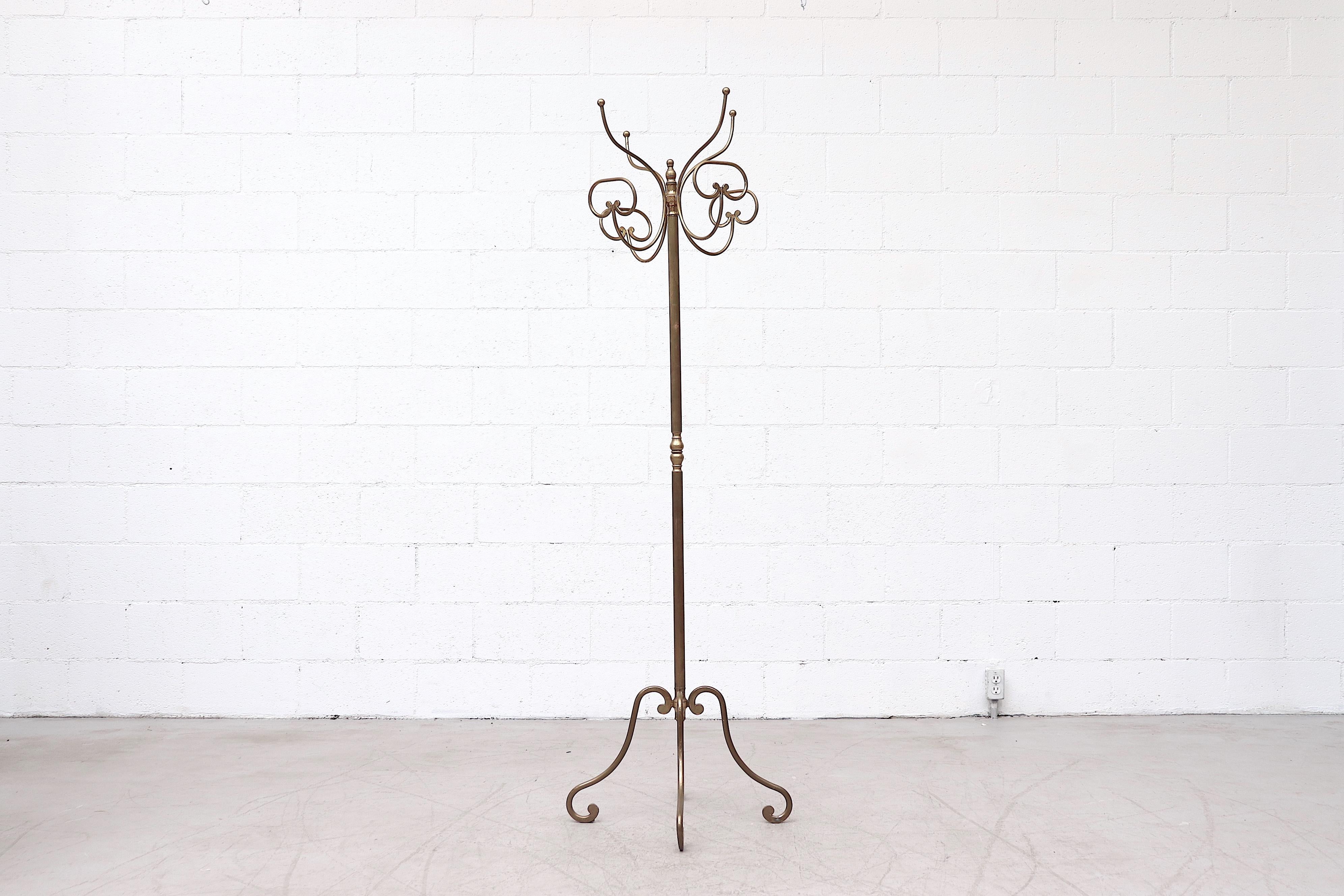 Midcentury Italian brass coat racks with rotating tops and ribbed stems, curved hooks and matching brass legs. In original condition with nice patina and some wear consistent with age and use. 1 available.
