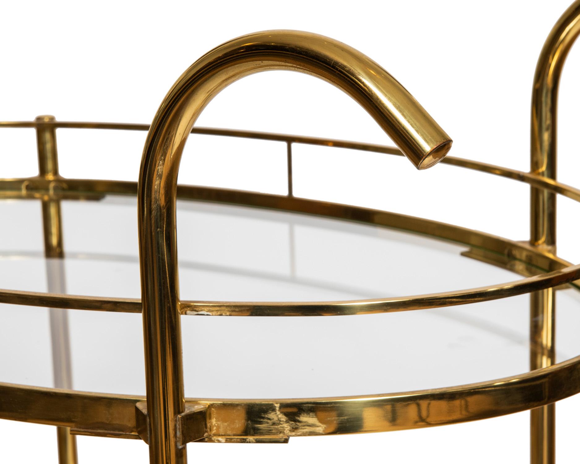 An elegant deco style oval brass bar cart with curved 