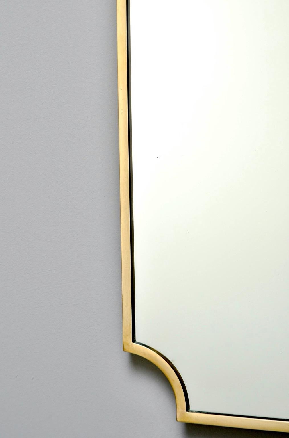 Tall and narrow Italian brass framed mirror, circa 1960. Wood backing. Unknown maker. Very good vintage condition with scattered minor wear to mirror and brass frame. 

Actual mirror size: 34.75” H x 15” W.