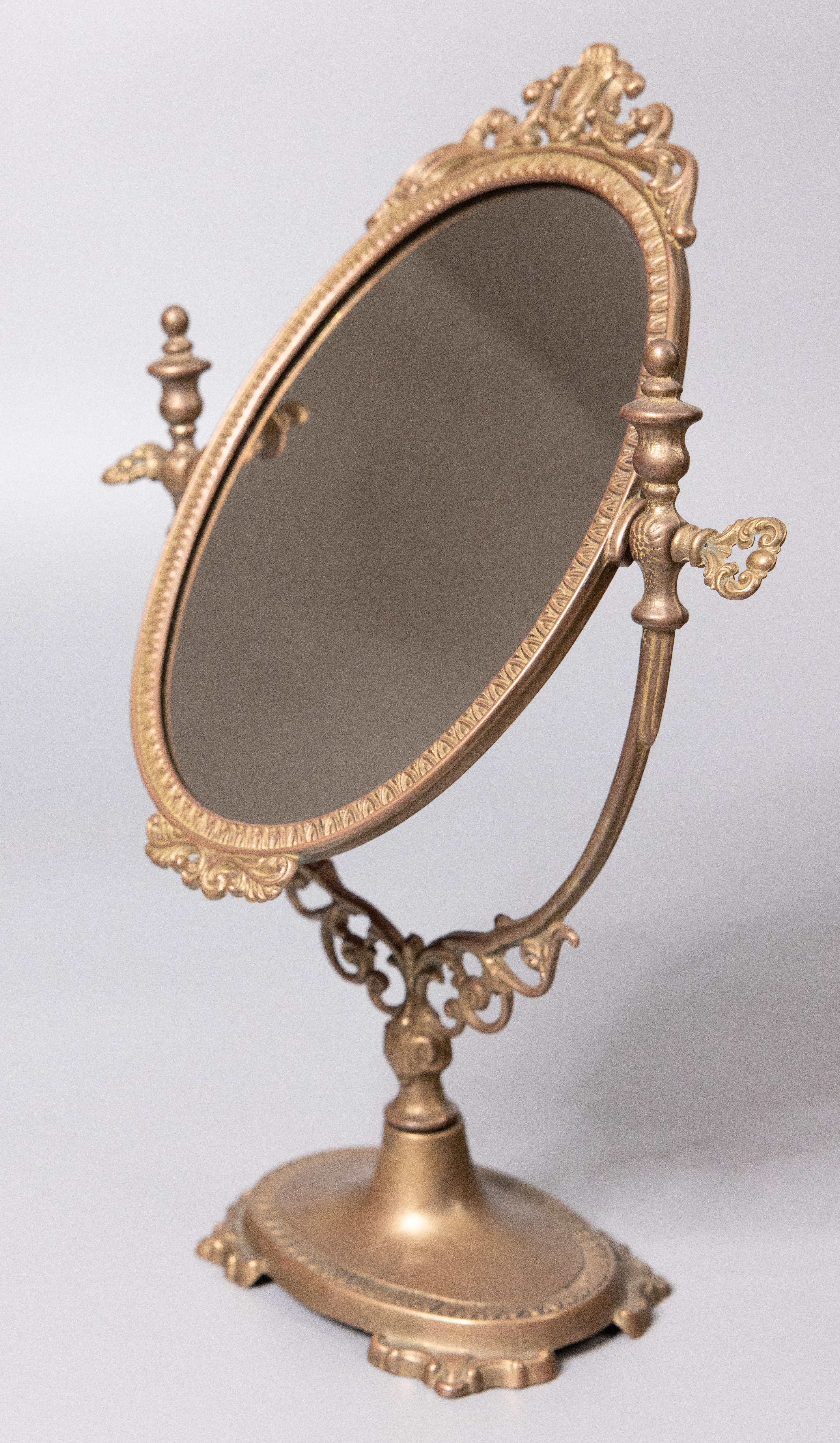 A gorgeous vintage Italian Rococo style brass dressing tabletop swivel mirror with ornate knobs to adjust the angle. 