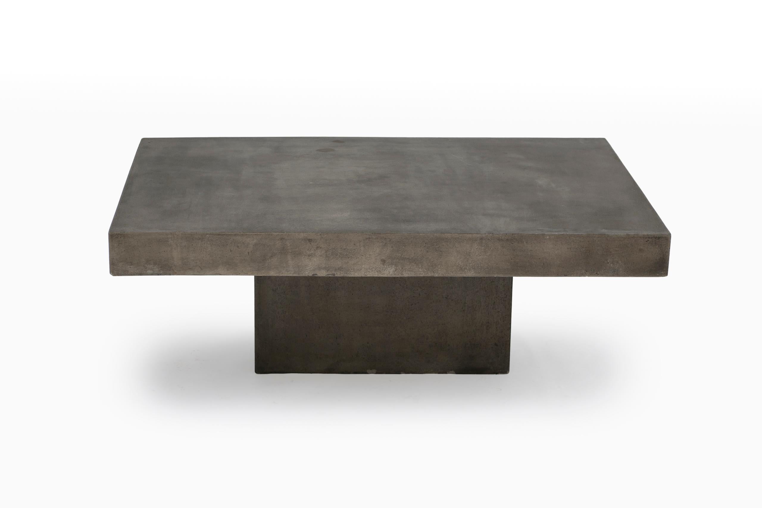 Table en béton coulé à la main de style brutaliste.
Cette pièce sculpturale présente un solide plateau rectangulaire soutenu par deux pieds en forme de blocs, soulignant la matérialité brute et la simplicité géométrique caractéristiques du design