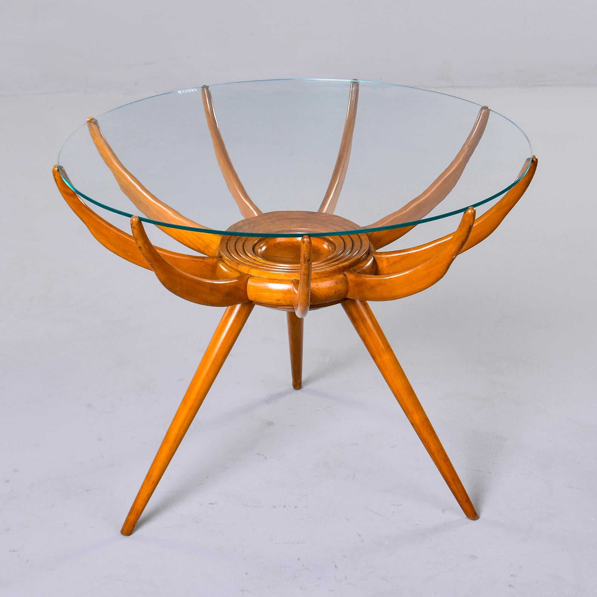 Iconic wood and glass spider leg side, coffee or cocktail table designed by Carlo De Carli. Made in Italy in the late 1950s. Base has three tapered legs. Round glass top is supported by nine curved and tapered arms that are notched on the ends for