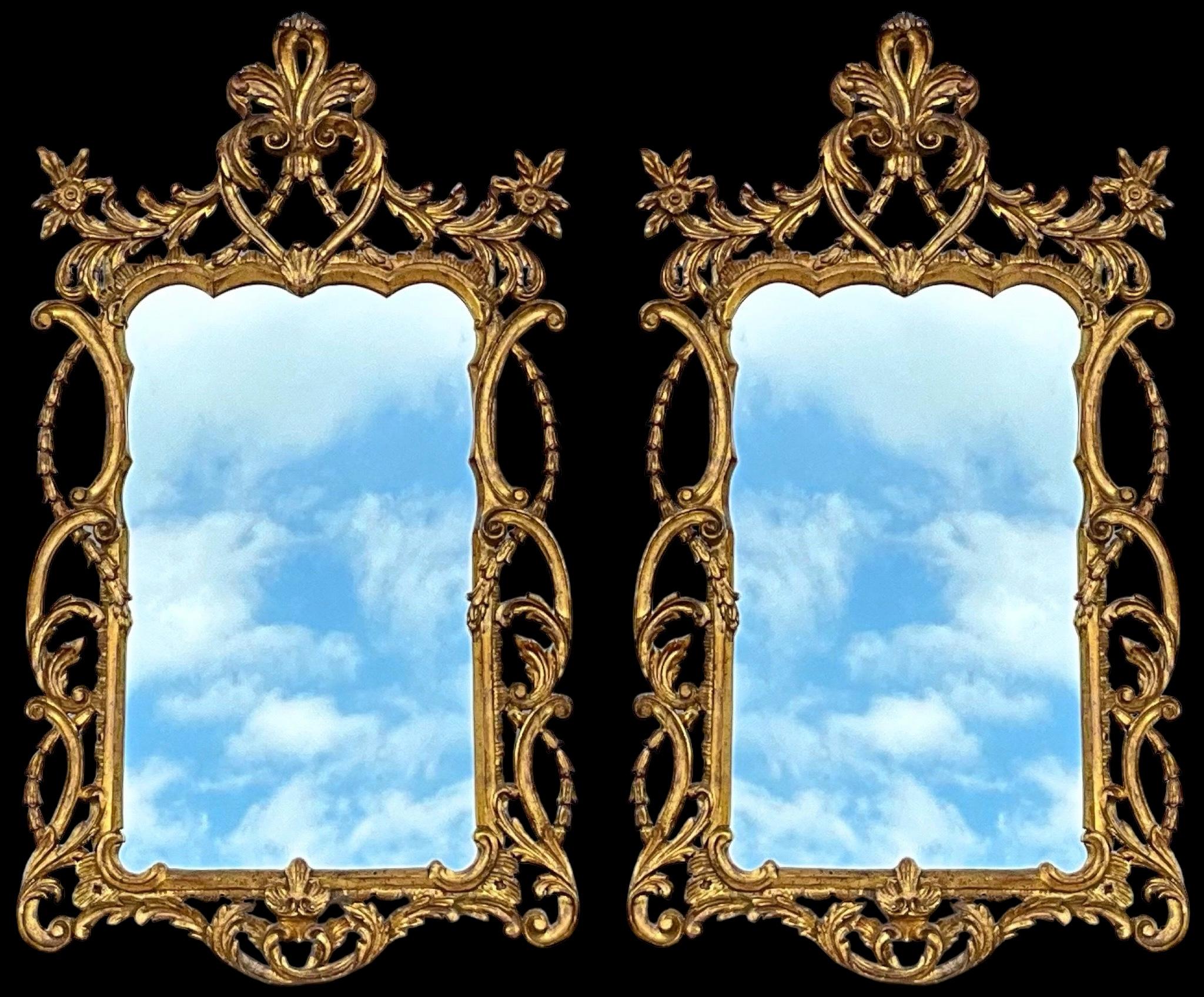 Il s'agit d'une belle paire de miroirs italiens en bois sculpté et doré datant du milieu du 20e siècle. Ils présentent un style français avec les décorations d'angle florales et le fronton à fleur de lys modifié. Ils ne portent aucune marque et sont