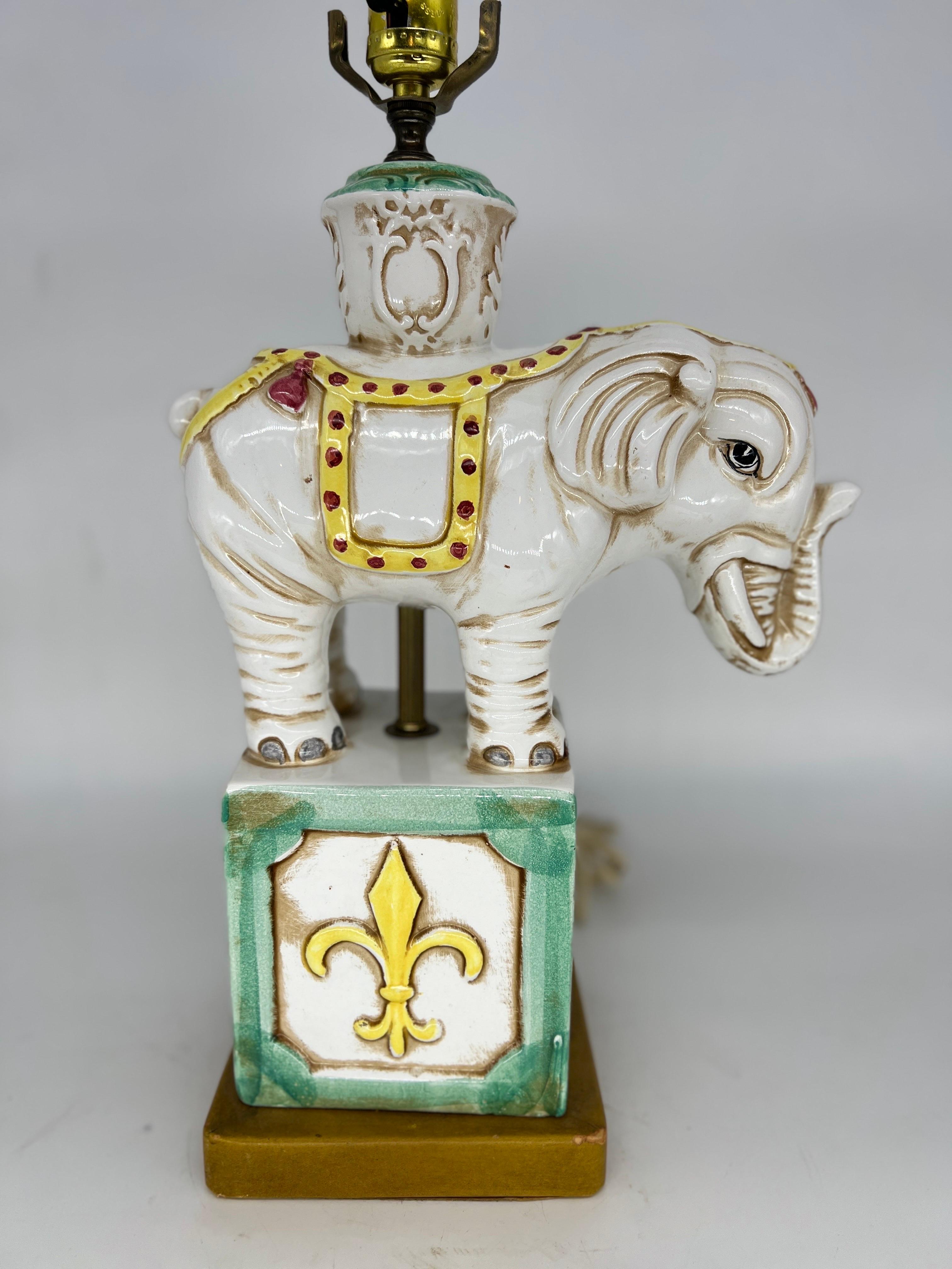 A great mid century ceramic table lamp in the form of an elephant. Fleur de lis style element to plinth and mounted to a leather base. Fully operational.