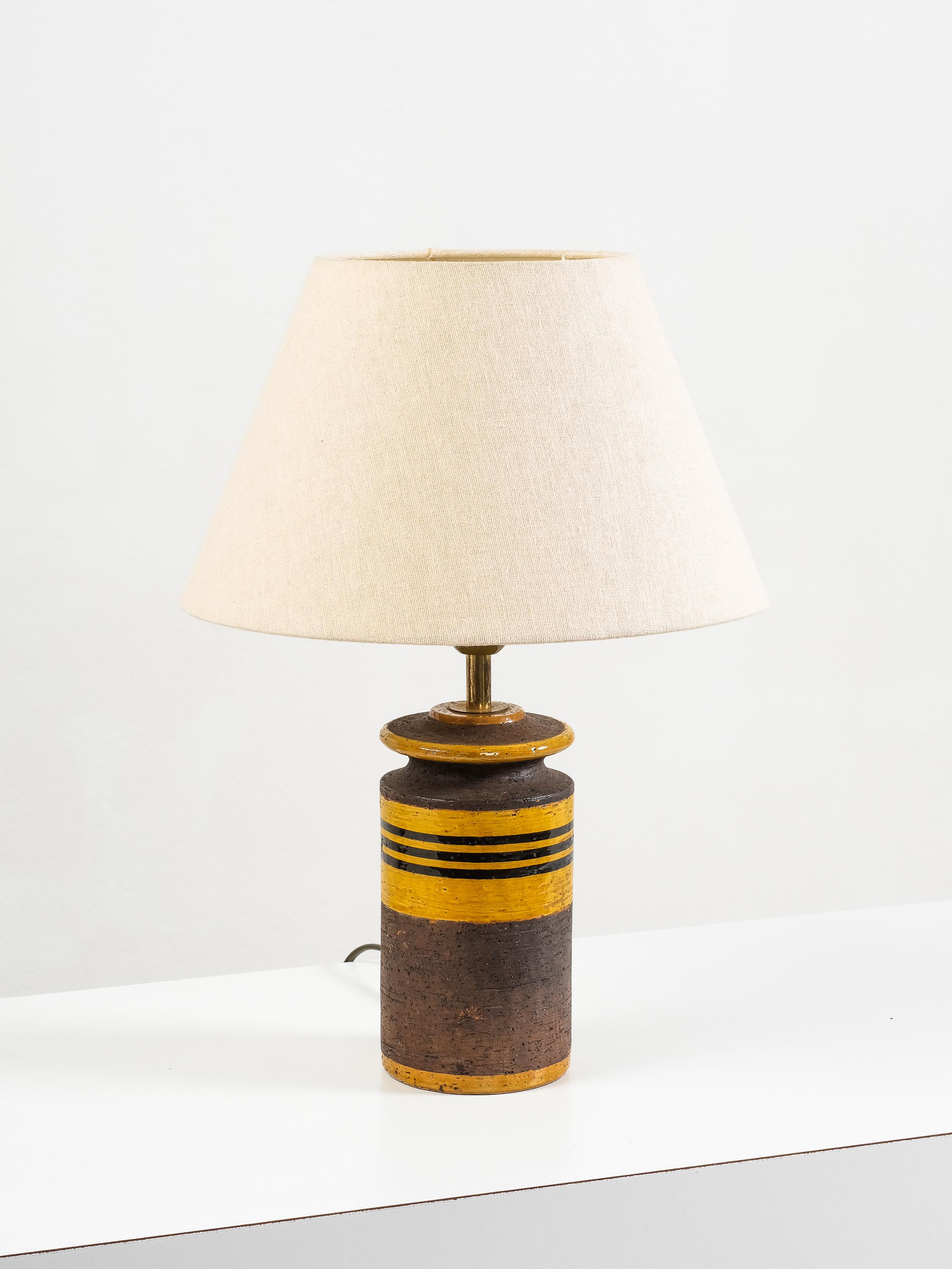 Lampe de table en céramique italienne des années 1960-70 avec une décoration rayée audacieuse : une glaçure sombre texturée contrebalancée par des rayures jaunes et brunes vives. L'interaction entre la surface terreuse et les détails graphiques