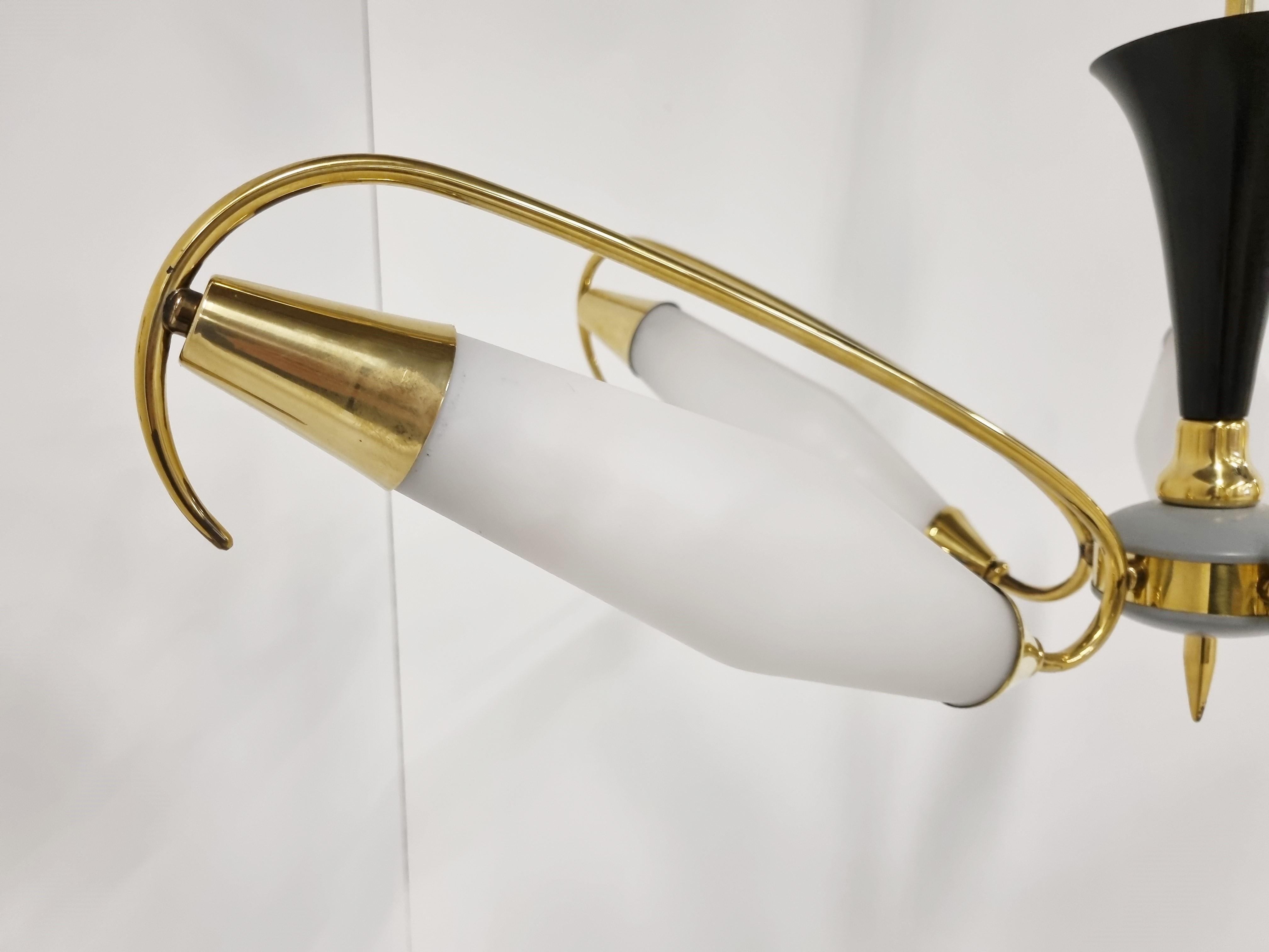 Mid century brass chandelier with 5 arms and white glass shades. 

Striking design and it emits a beautiful light.

Good condition.

Tested and ready to use. 

Works with two e14 light bulbs.

1960s - Italy

Dimensions:

Height: