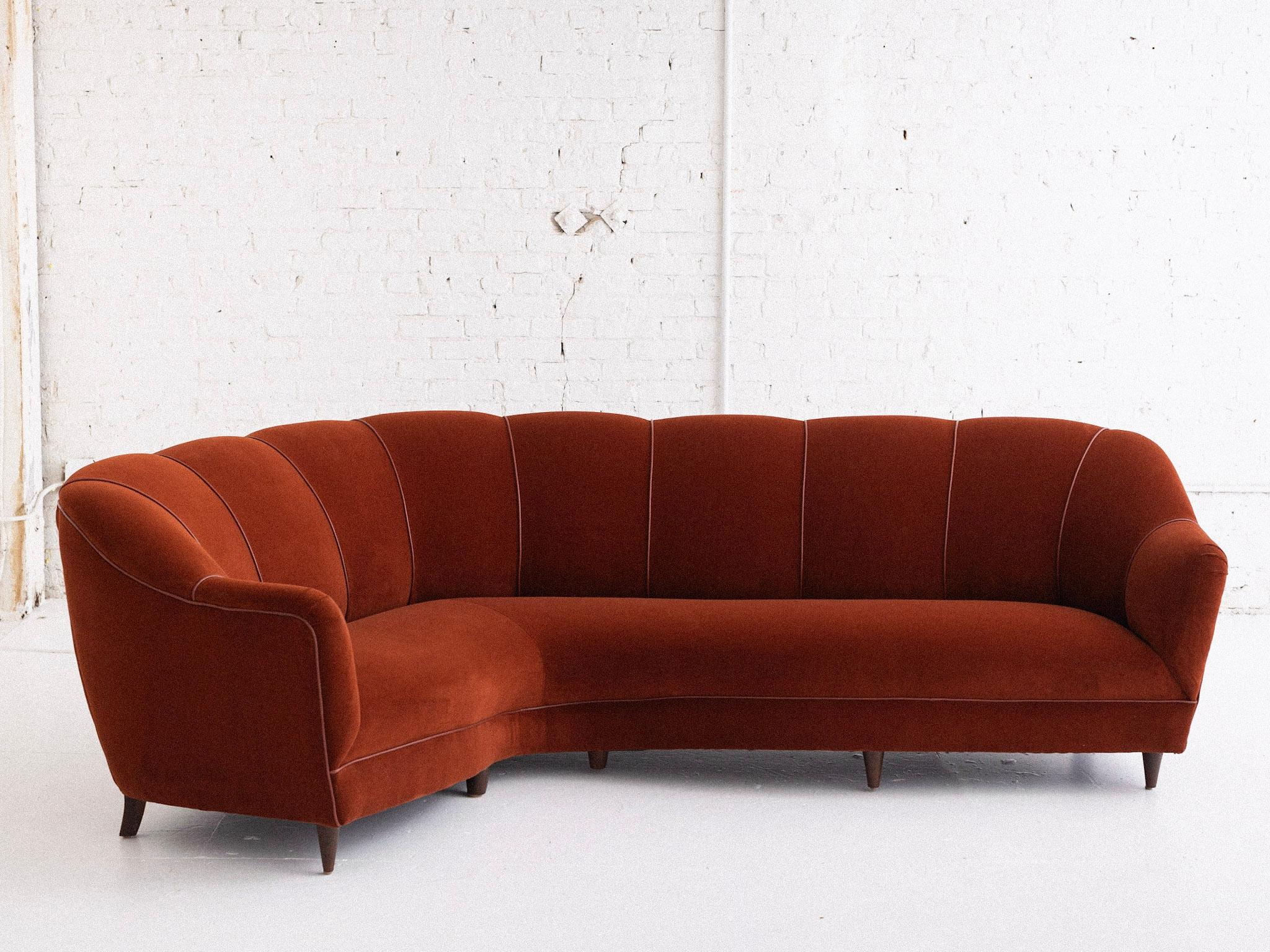 A midcentury Italian channel back sofa. Newly upholstered in a rust cotton velvet with leather trim. Curved corner shape. Sourced outside of Florence, Italy.