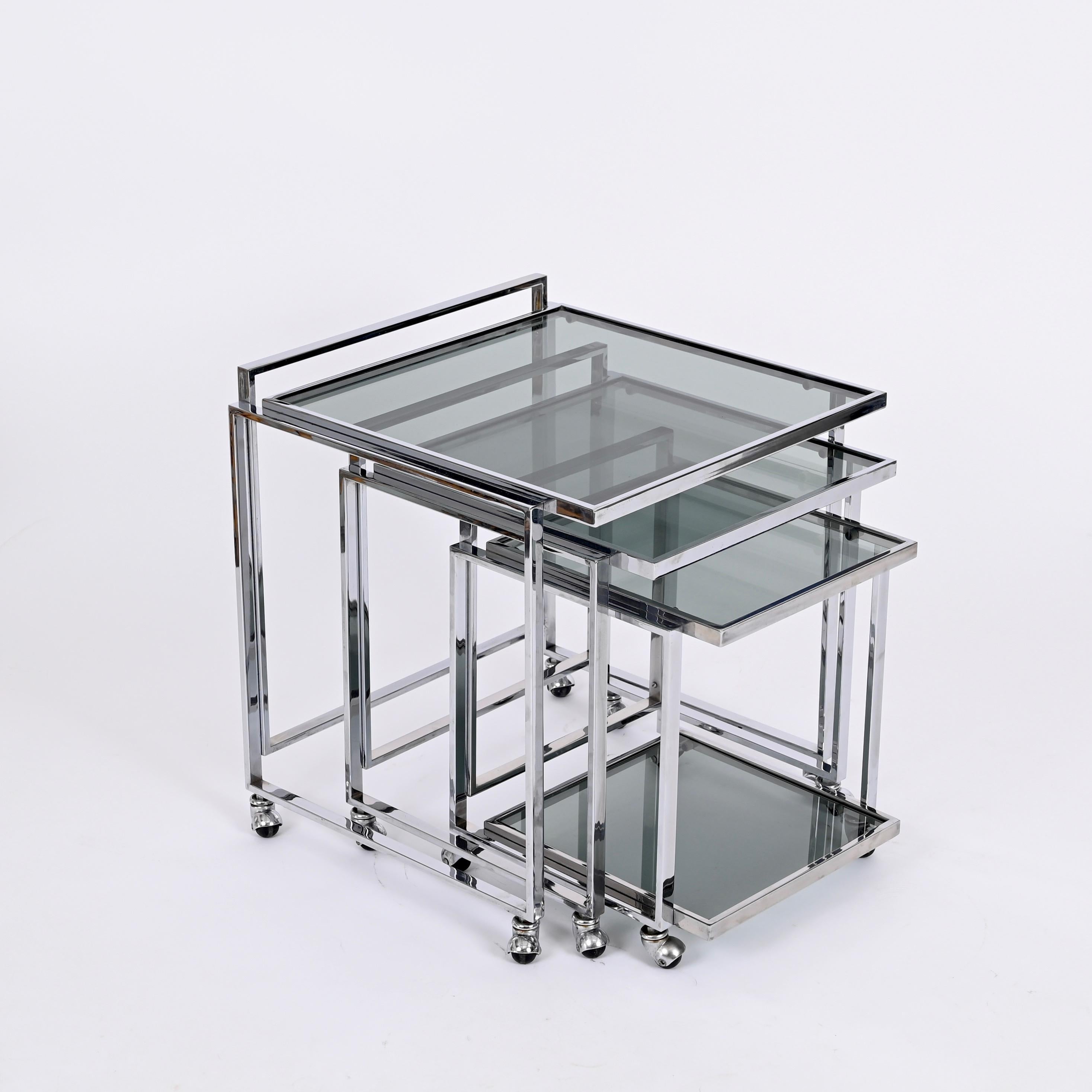 Stunning set of three nesting tables with wheels fully made in chromed steel with smoked glass top. This stylish nesting tables were made in Italy during thje 1970s.

These three versatile nesting tables feature a square shaped structure in chrom