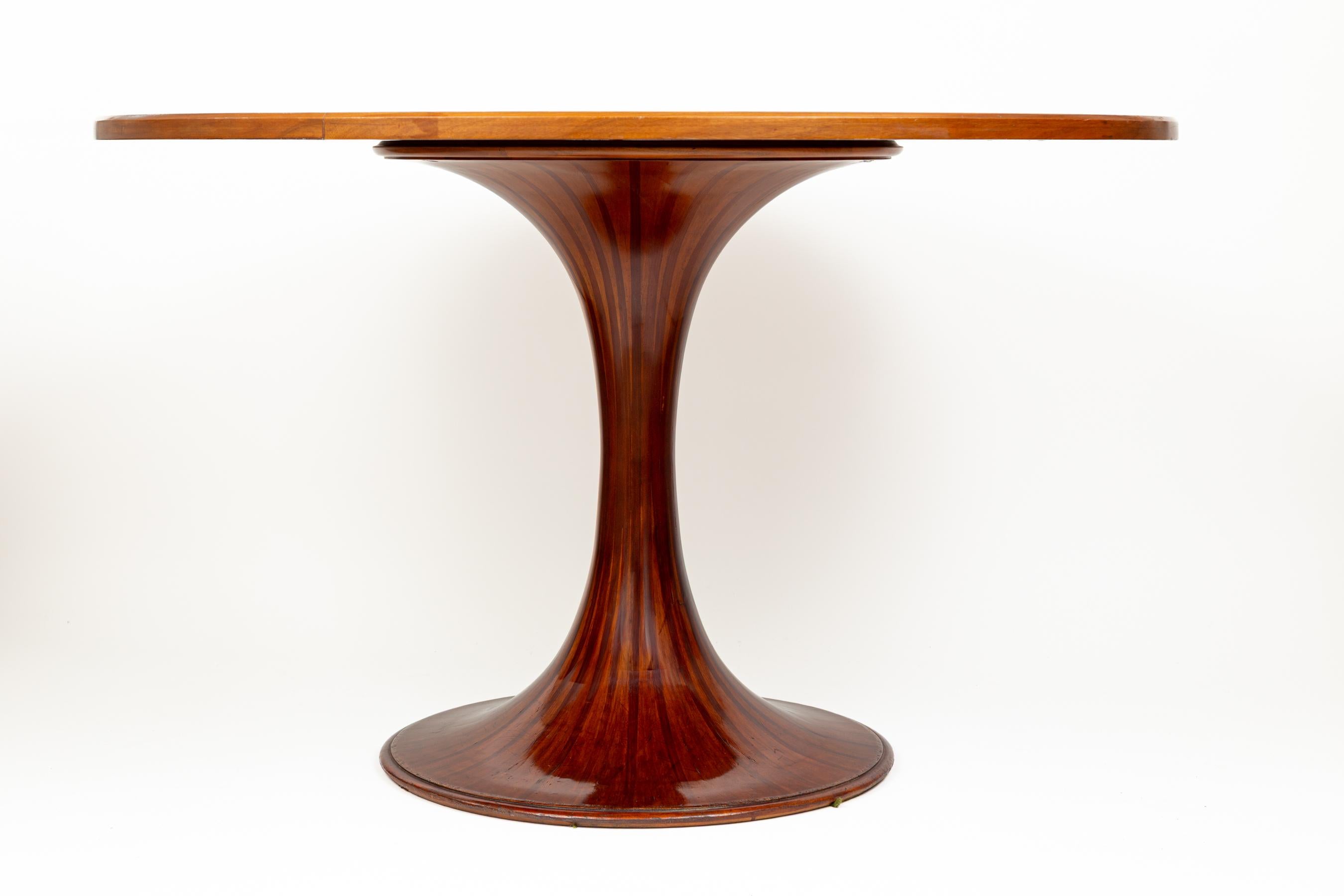 Una elegante mesa de comedor modelo 2101 diseñada por Luigi Massoni y fabricada por Mobilia, Italia 1959. Esta mesa de comedor redonda con pedestal tiene una espectacular base en forma de tulipán a rayas, rematada con un acentuado borde enrollado en