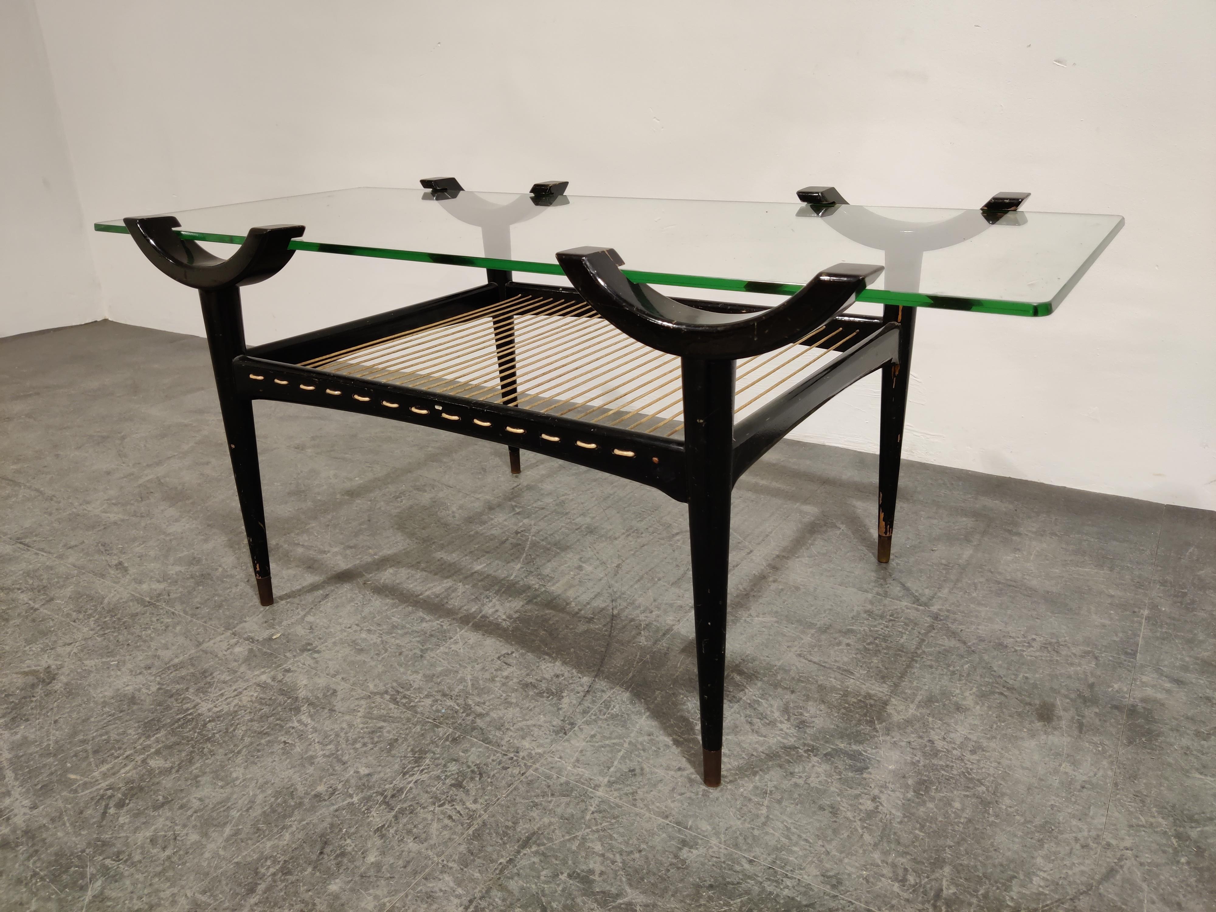 Rare midcentury lacquered wooden floating top coffee table.

The glass top slides into the supporting arms creating a unique way of suporting the glass and making it a smart looking table.

The coffee table has also a magazine storage space made