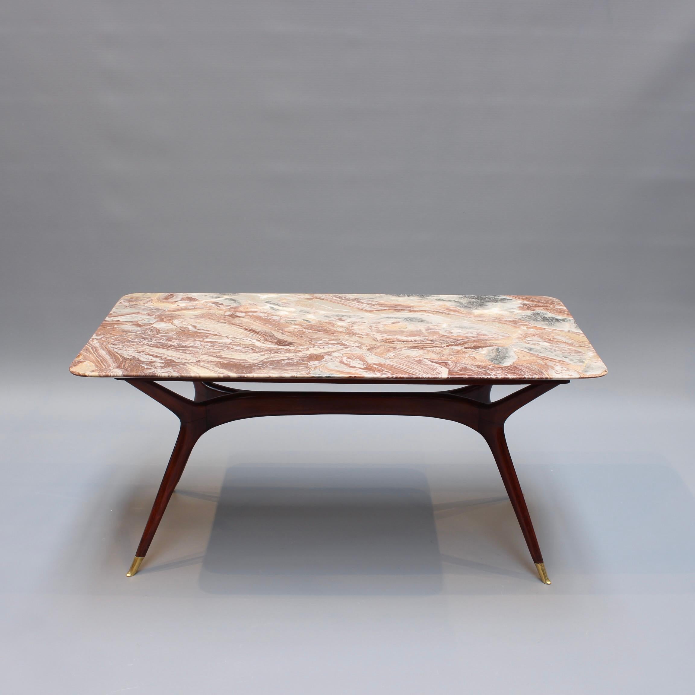 Mid-Century Italian coffee table attributed to Ico Parisi (1950s). A mostly reddish, rectangular marble top sits upon a very stylish base consisting of Parisi's iconic wooden legs and brass feet. The legs are constructed using softwoods often cut