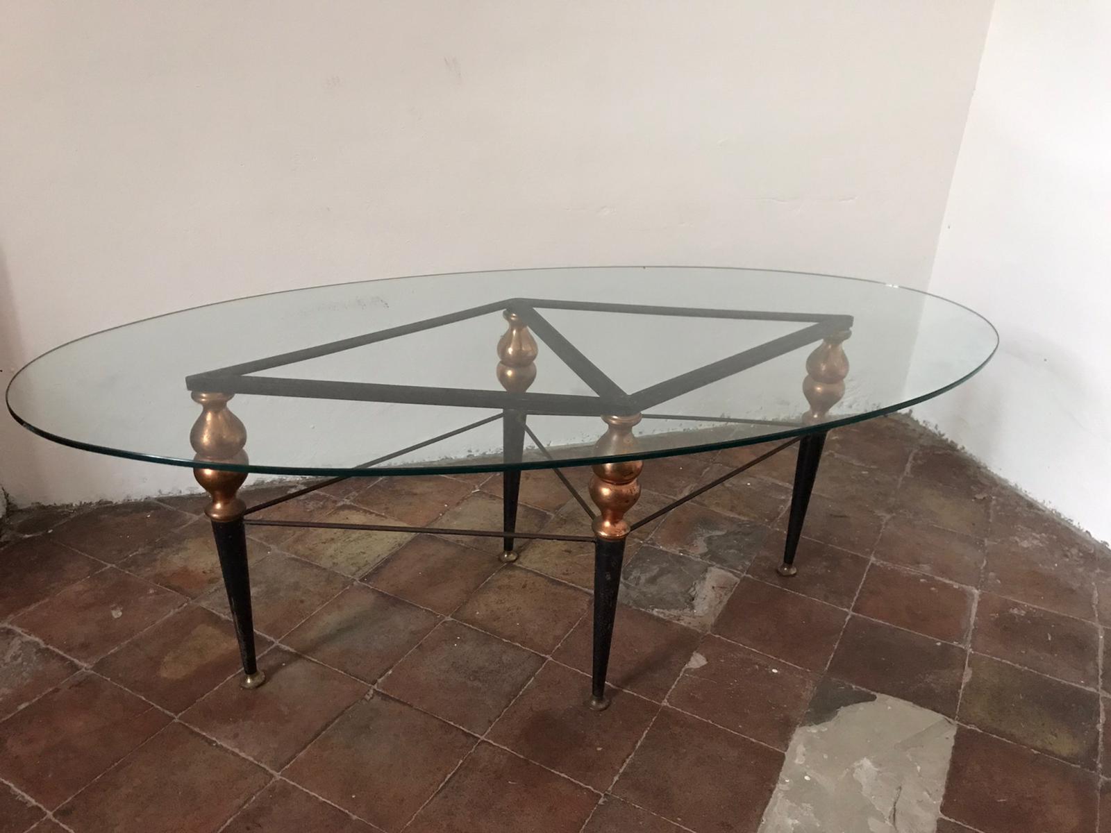 Midcentury Italian coffee table in black metal with brass hardware and clear oval glass top.