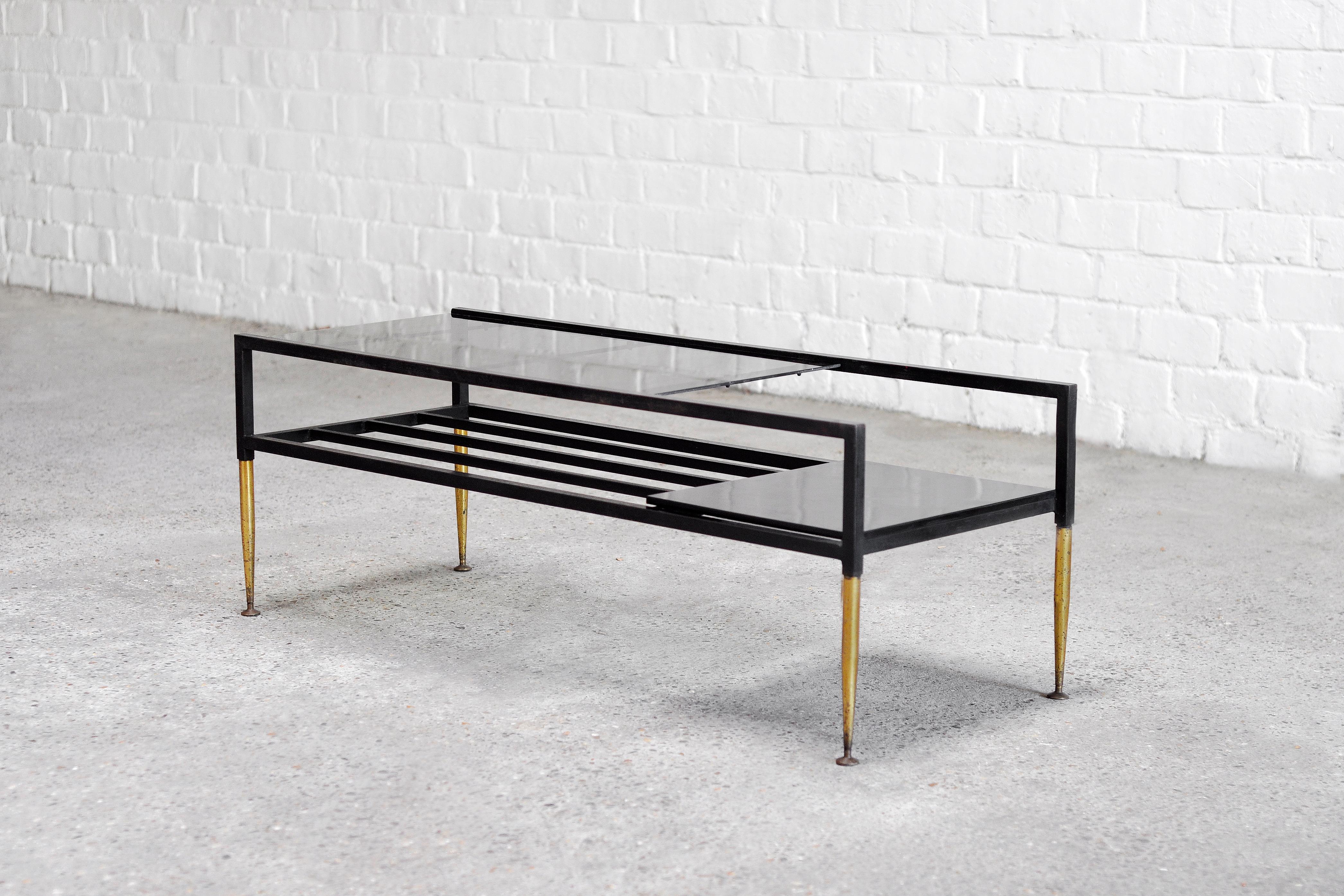 A unique 1960's Italian designer coffee table that features a very elegant and interesting design. Crafted with a lacquered metal frame and supported by conic brass legs that are typical for italian design of this period.  This piece is perfect for