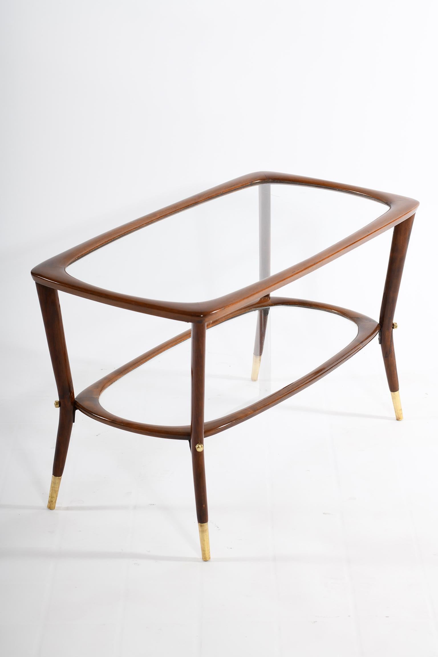 Midcentury Italian coffee table with underlying glass shelf for books and magazines, rounded structure in solid walnut with brass details and feet.
The size of this table and the proportion are very interesting, as well as the light and functional