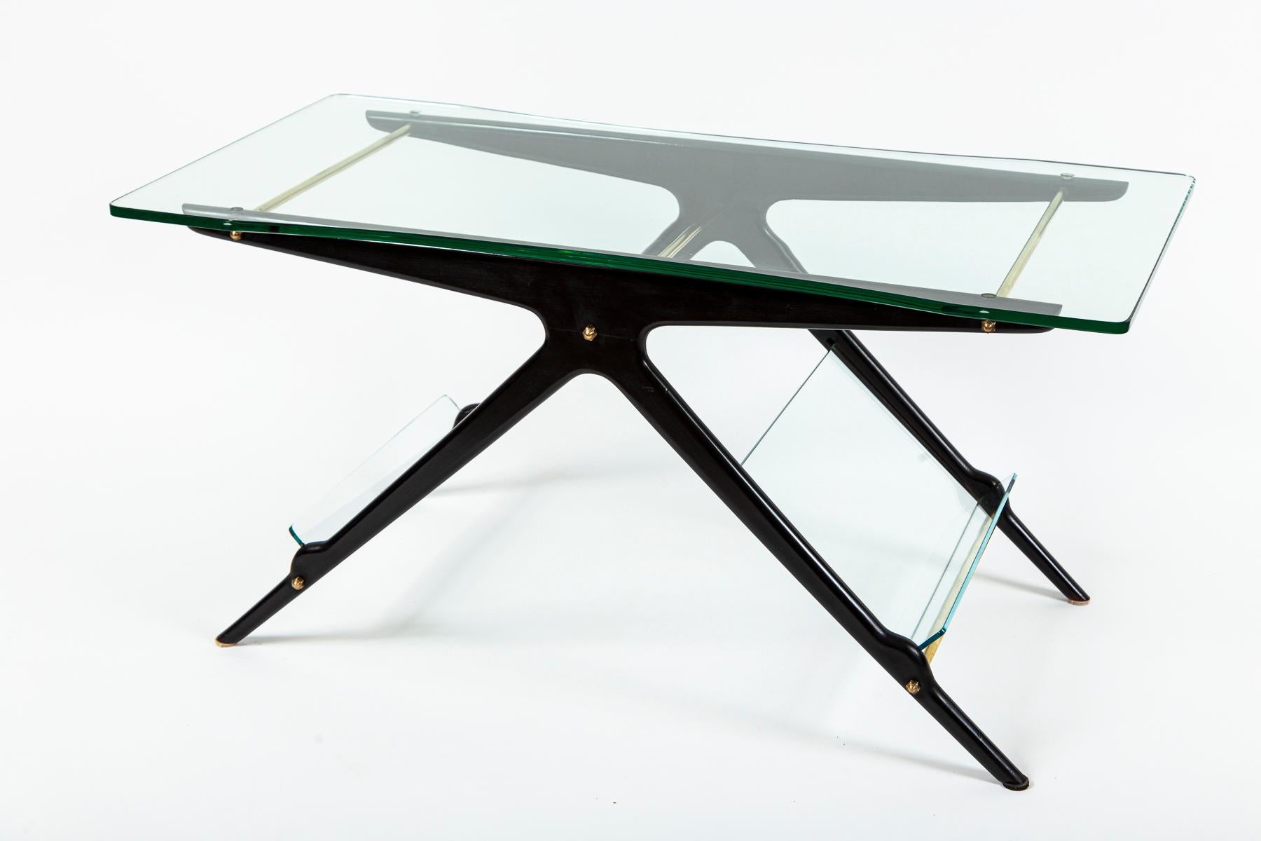 Esta mesa de centro italiana fue diseñada en los años 50 por Cesare Lacca. El armazón de madera lacada en negro está construido en forma de T ensanchada. Entre los pares de patas se insertan placas de cristal a modo de revisteros. El tablero de la