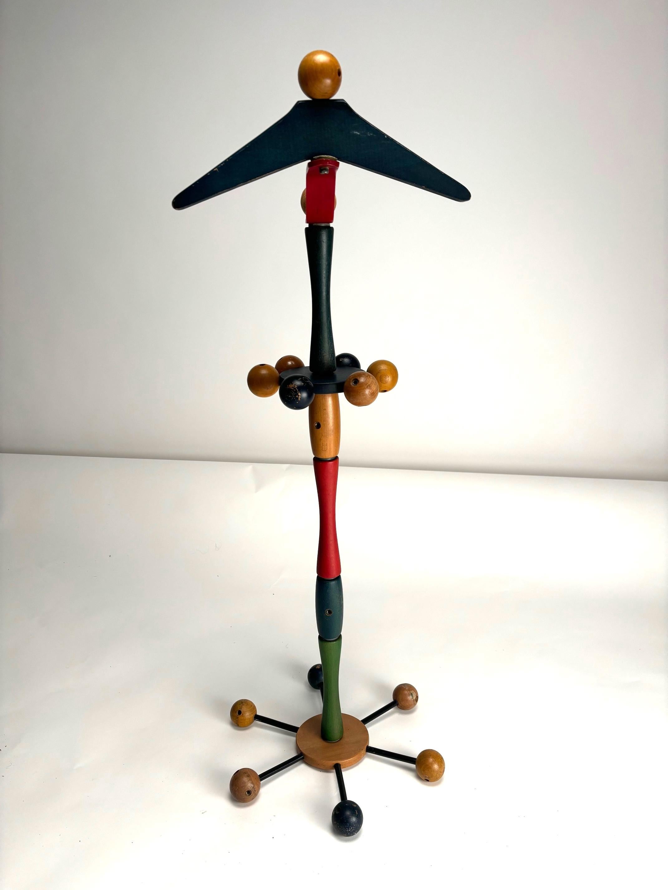 This Reguitti children's coat rack features a playful and colorful design, crafted from painted wood. The vertical structure is composed of segments in different shades, including red, green, blue, and brown, creating a vibrant effect. The top