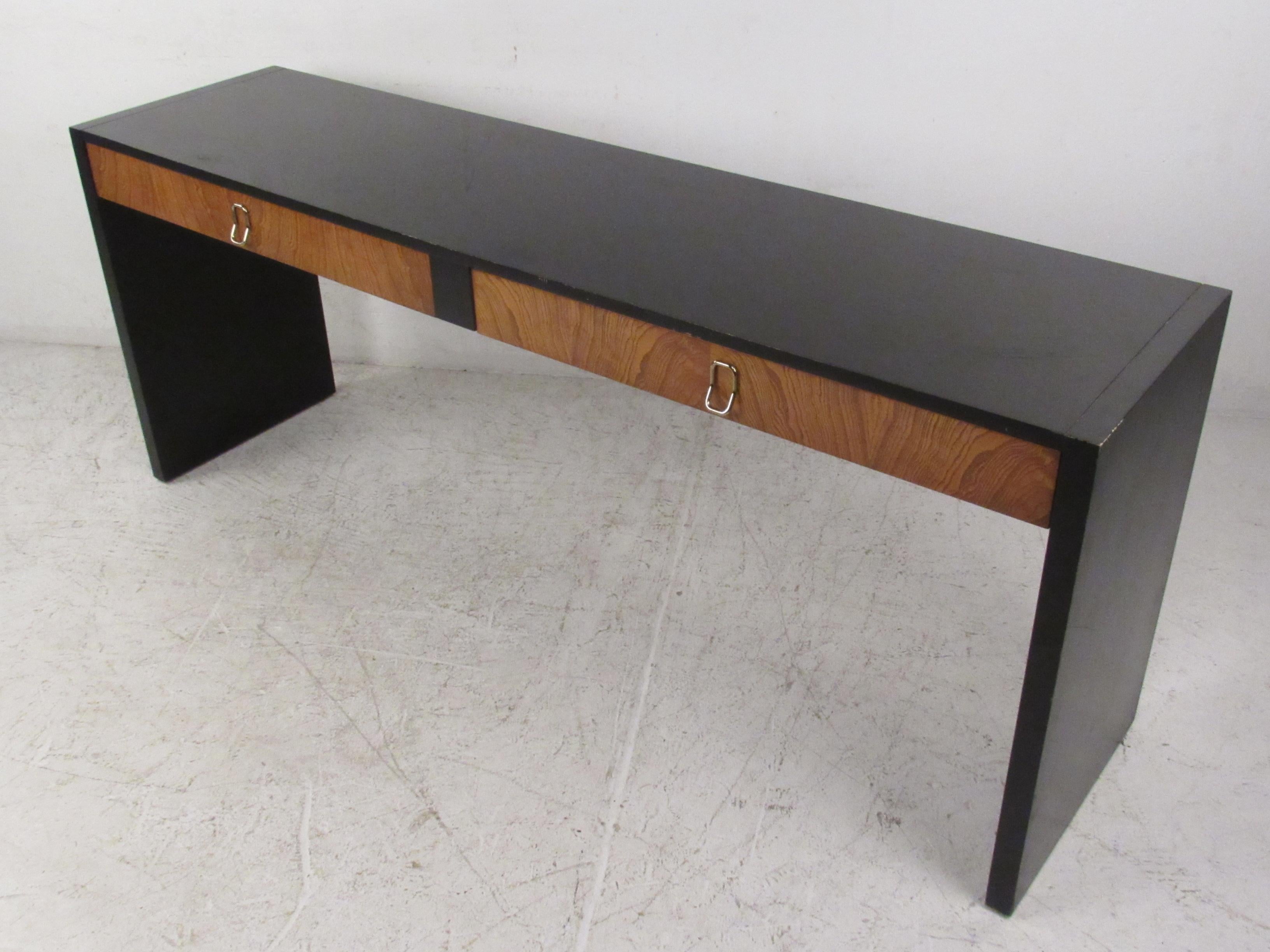 This stunning vintage modern hall table features two large drawers with unusual metal pulls. A lovely two-tone design that is sure to make a lasting impression in any setting. This versatile mid-century piece functions as a vanity, a desk, or a