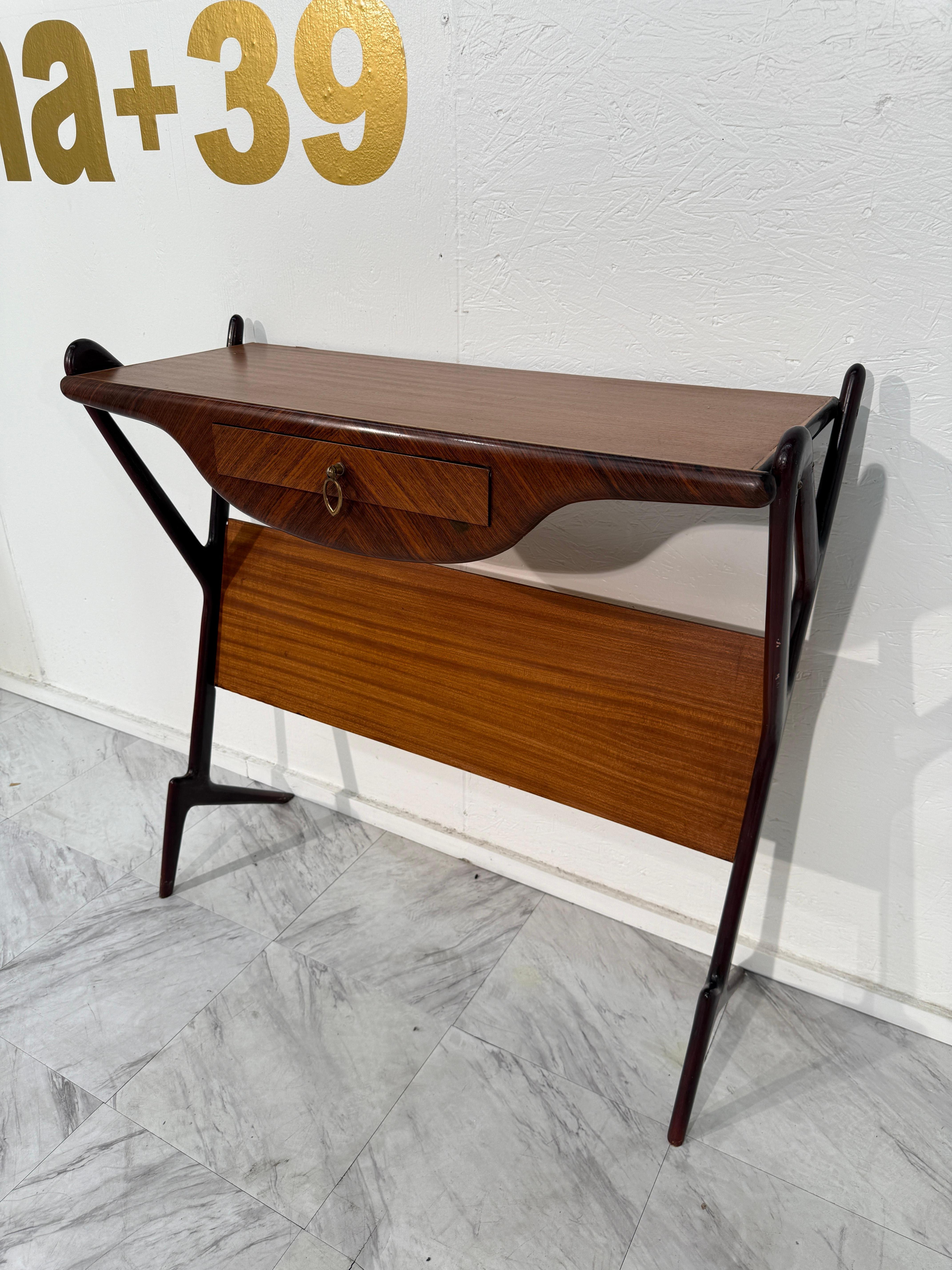 Una raffinata consolle italiana di metà secolo, realizzata negli anni '50, che mette in mostra l'elegante artigianato e il design funzionale dell'epoca. La consolle presenta una silhouette elegante e lineare con un unico cassetto centrale,