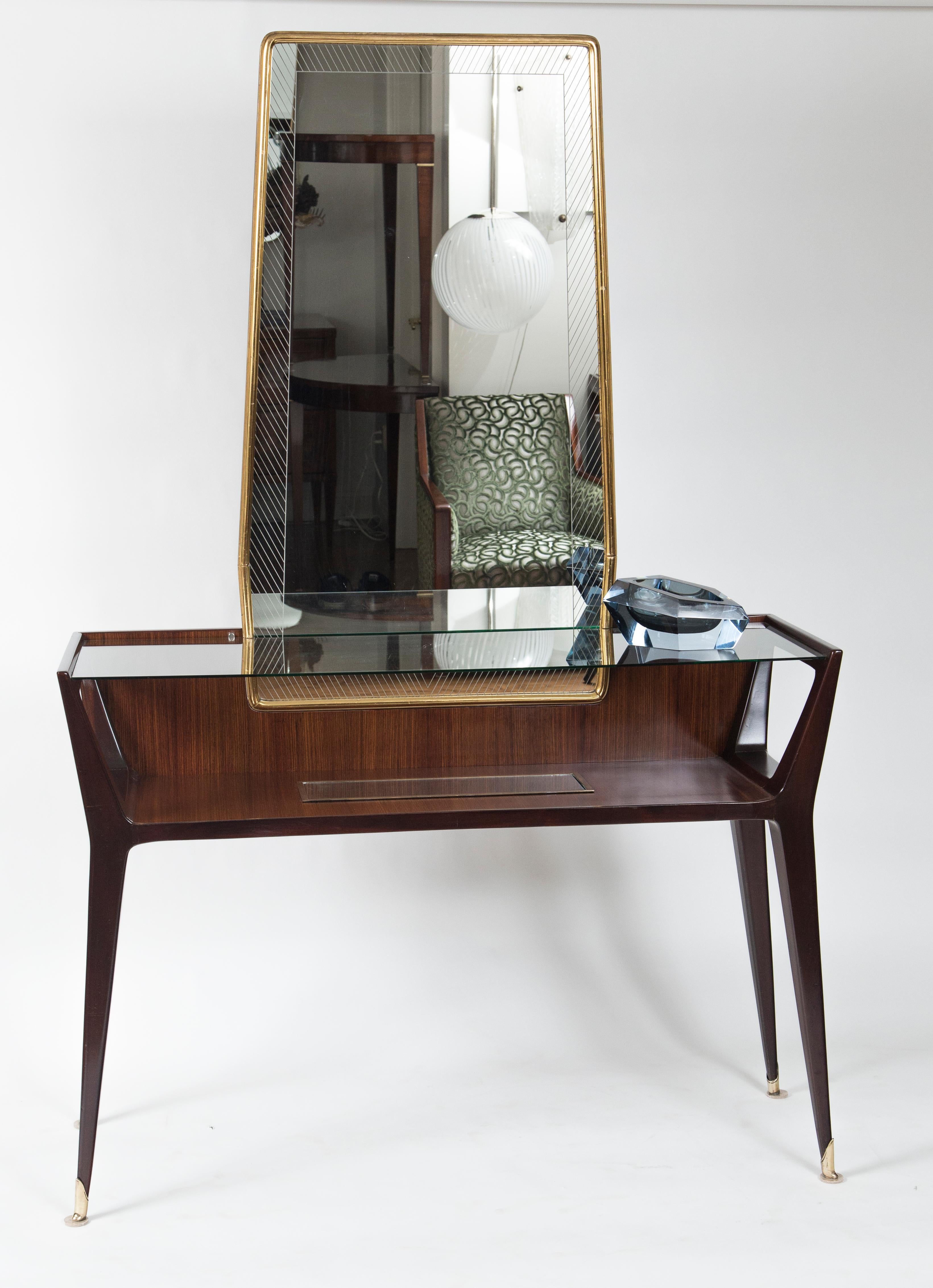 Wonderful floating glass top rosewood console table with a glass encased shelf below finishing on angular legs with bronze sabots and above a detachable angular gilt mirror. Console looks great without mirror as well.
Origin: Italy
Manufacturer La