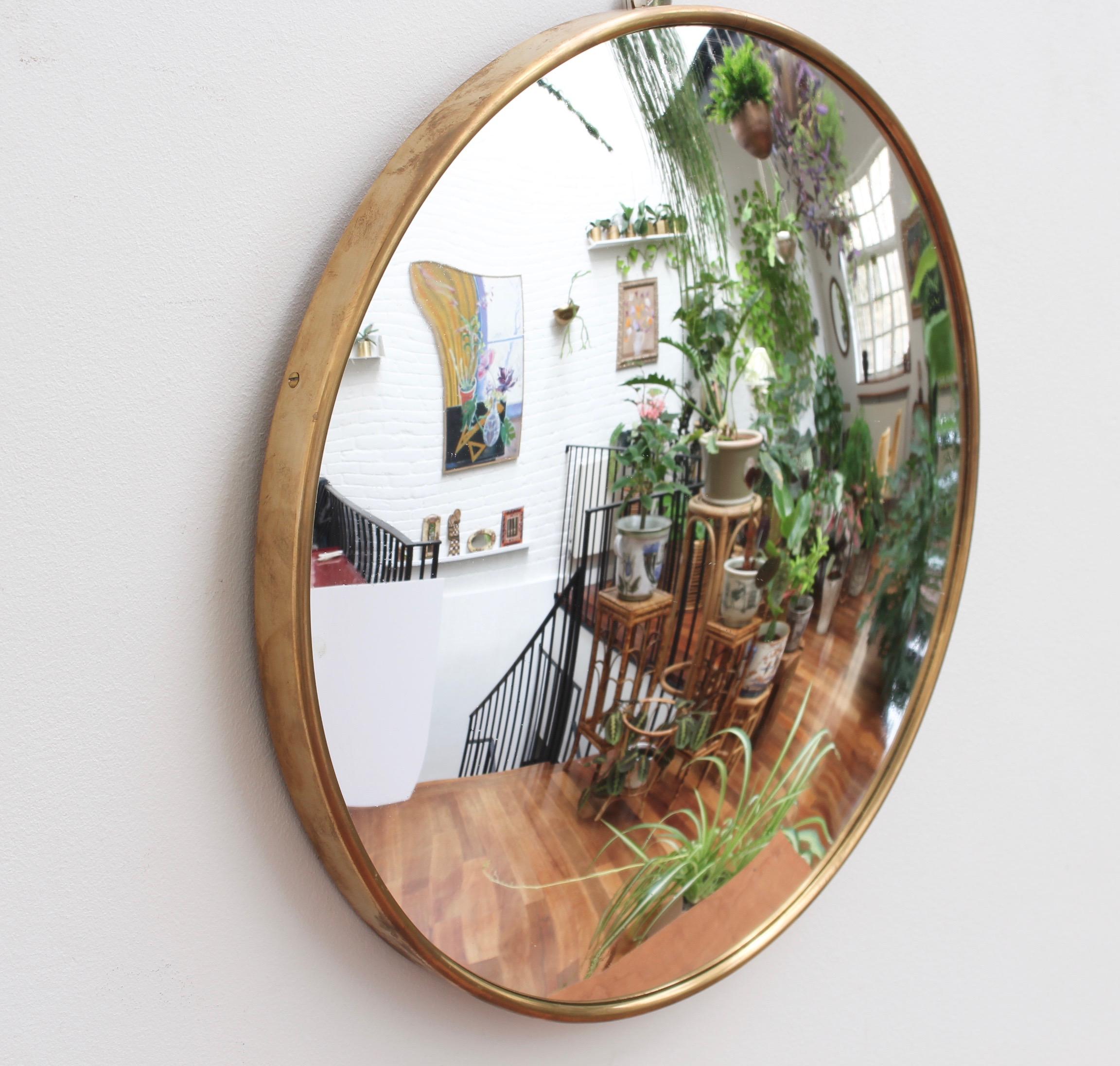 Midcentury Italian convex wall mirror with brass frame (circa 1950s). This relatively small mirror is simply elegant and characterful in a modern, Gio Ponti style. It is characterized by its circular shape with sensuous curves and convex glass. The