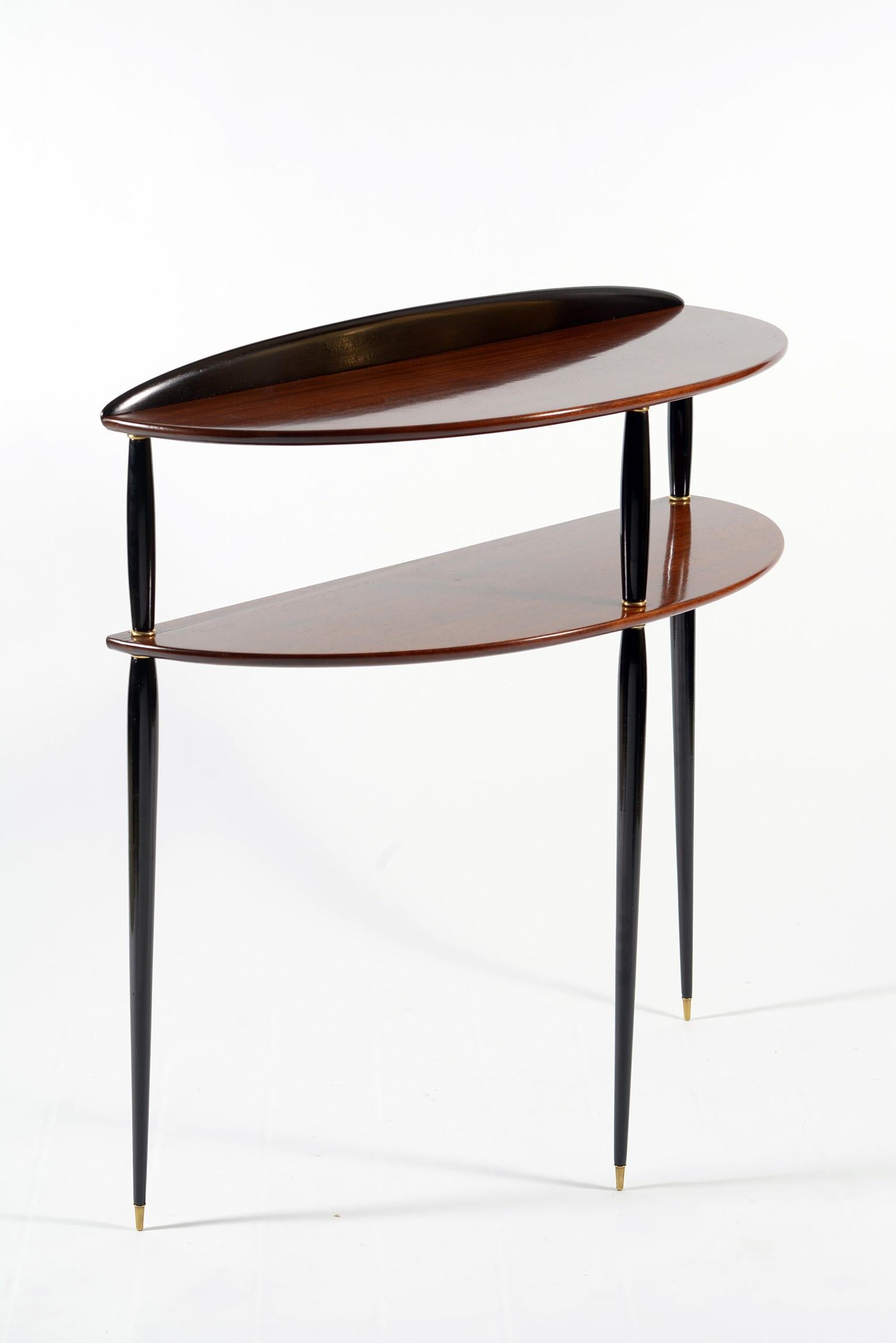 Slender Italian walnut console with double top in semi-round shape, three tapered legs in black lacquered wood interspersed with brass ring finishes and finished with conical tips always in brass, support the two floors and make this console