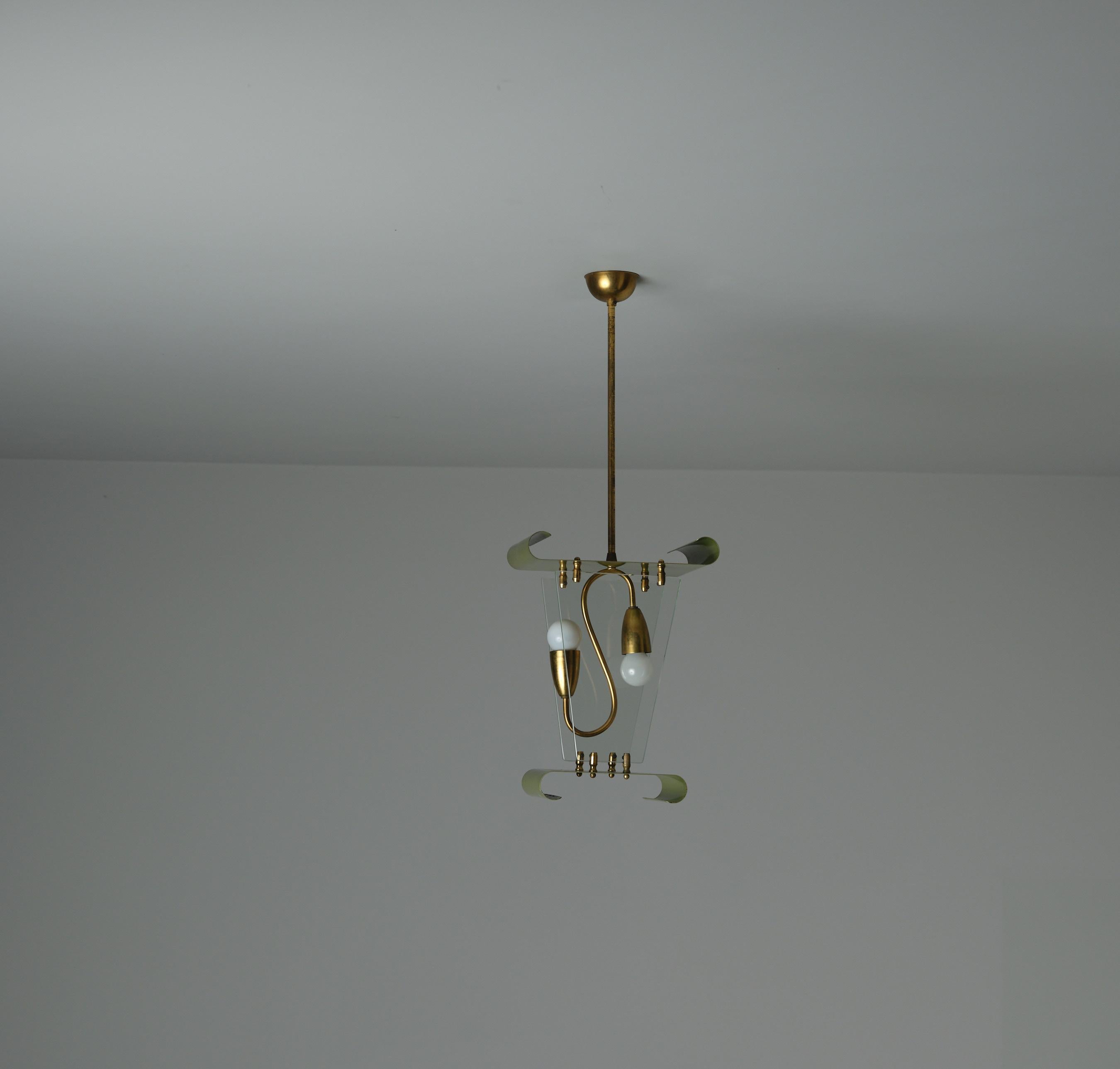  Questa lampada a sospensione italiana degli anni '50 presenta un design distintivo con una composizione strutturale che comprende elementi in metallo laccato verde piegato e ottone che mostrano una piacevole patina. L'apparecchio è appeso a una