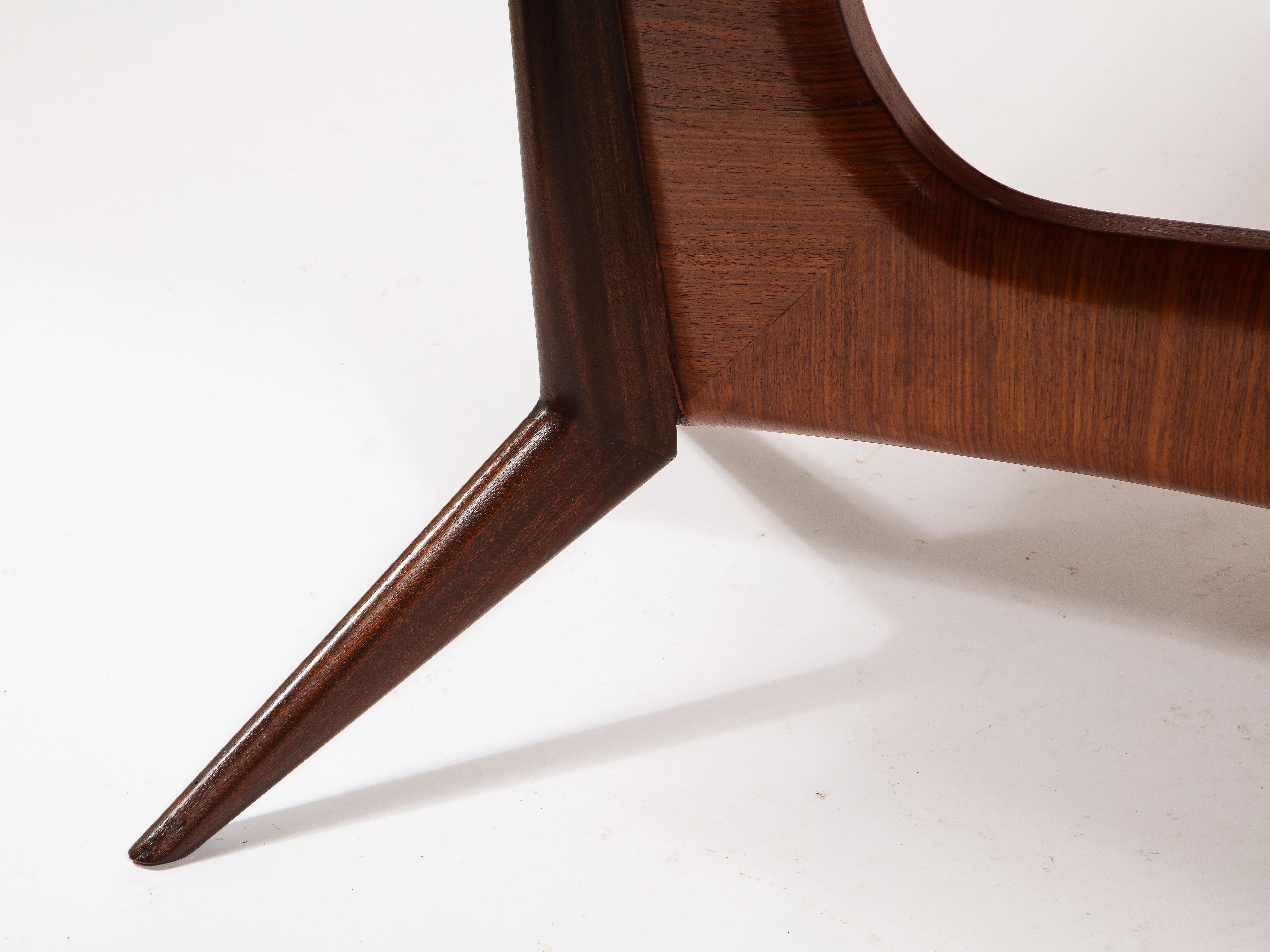 A sculptural dining table in rosewood and walnut with a reverse painted glass top.