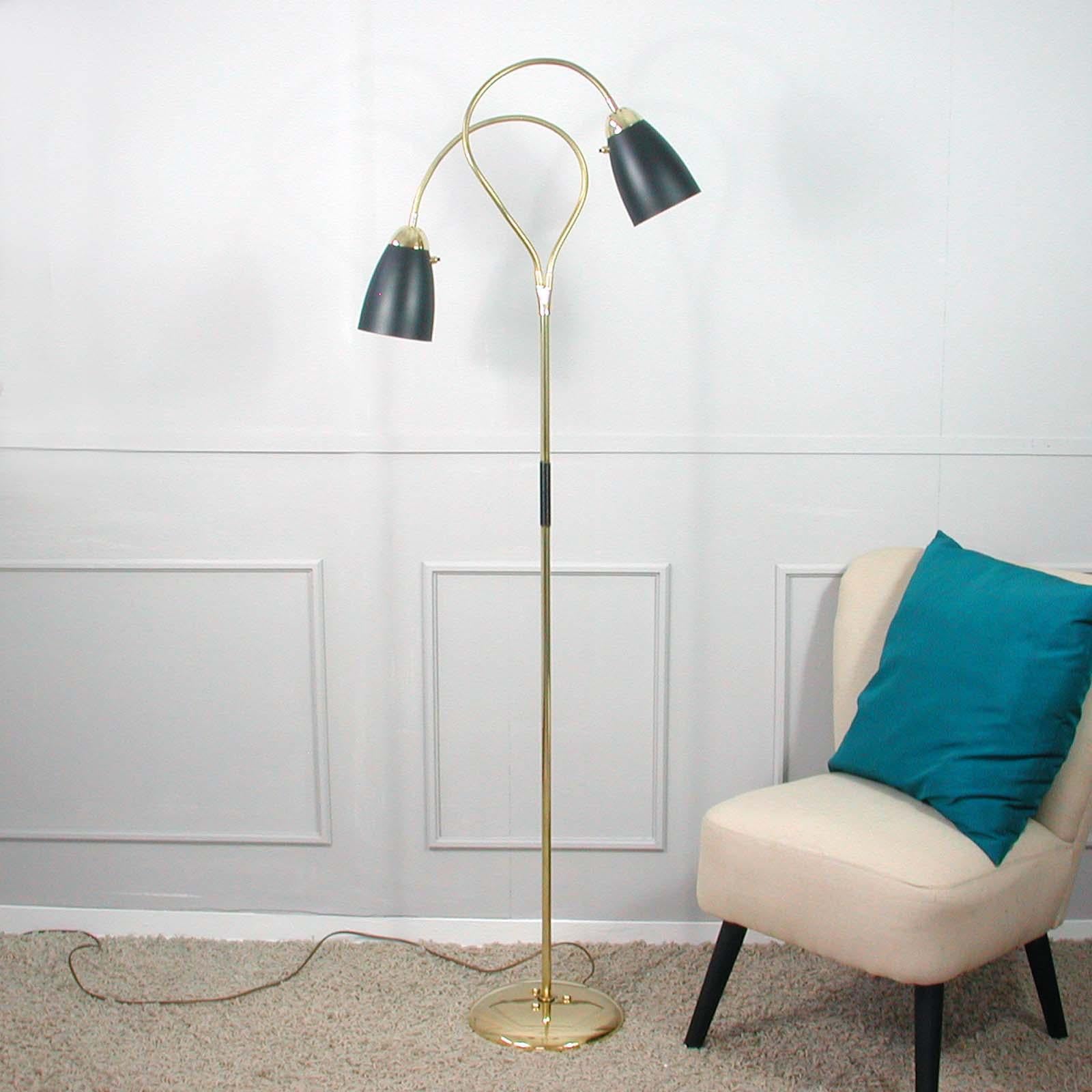 This midcentury brass double gooseneck floor lamp was made in Italy in the 1950s.

The lamp has got a round brass base and two adjustable gooseneck lamp arms with bullet shaped black lacquered shades. The shades have been refurbished and the brass