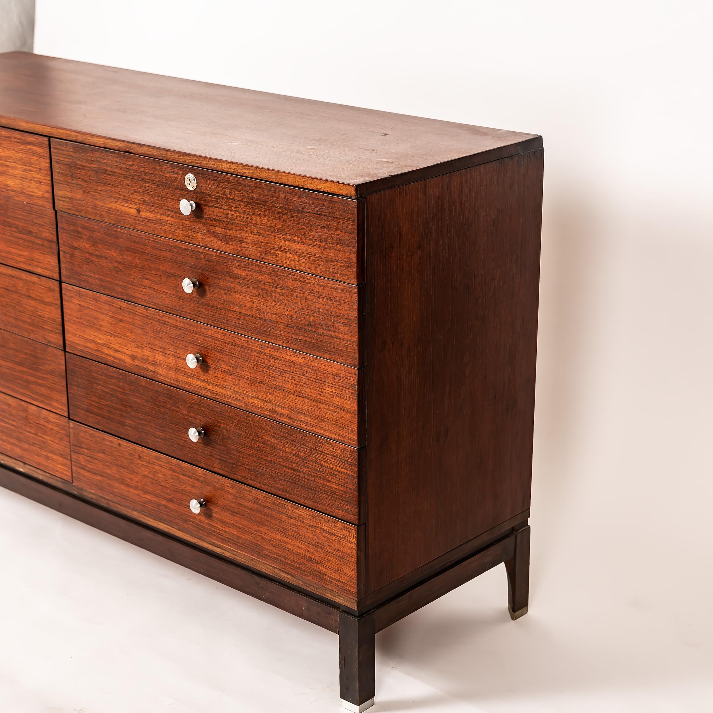 Exemple frappant du modernisme italien, cette rare commode a été conçue par Ico & Luisa Parisi pour MIM (Mobili Italiani Moderni) dans les années 1960. Fabriqué en bois richement grainé avec une façade minimaliste, il comprend neuf tiroirs avec des