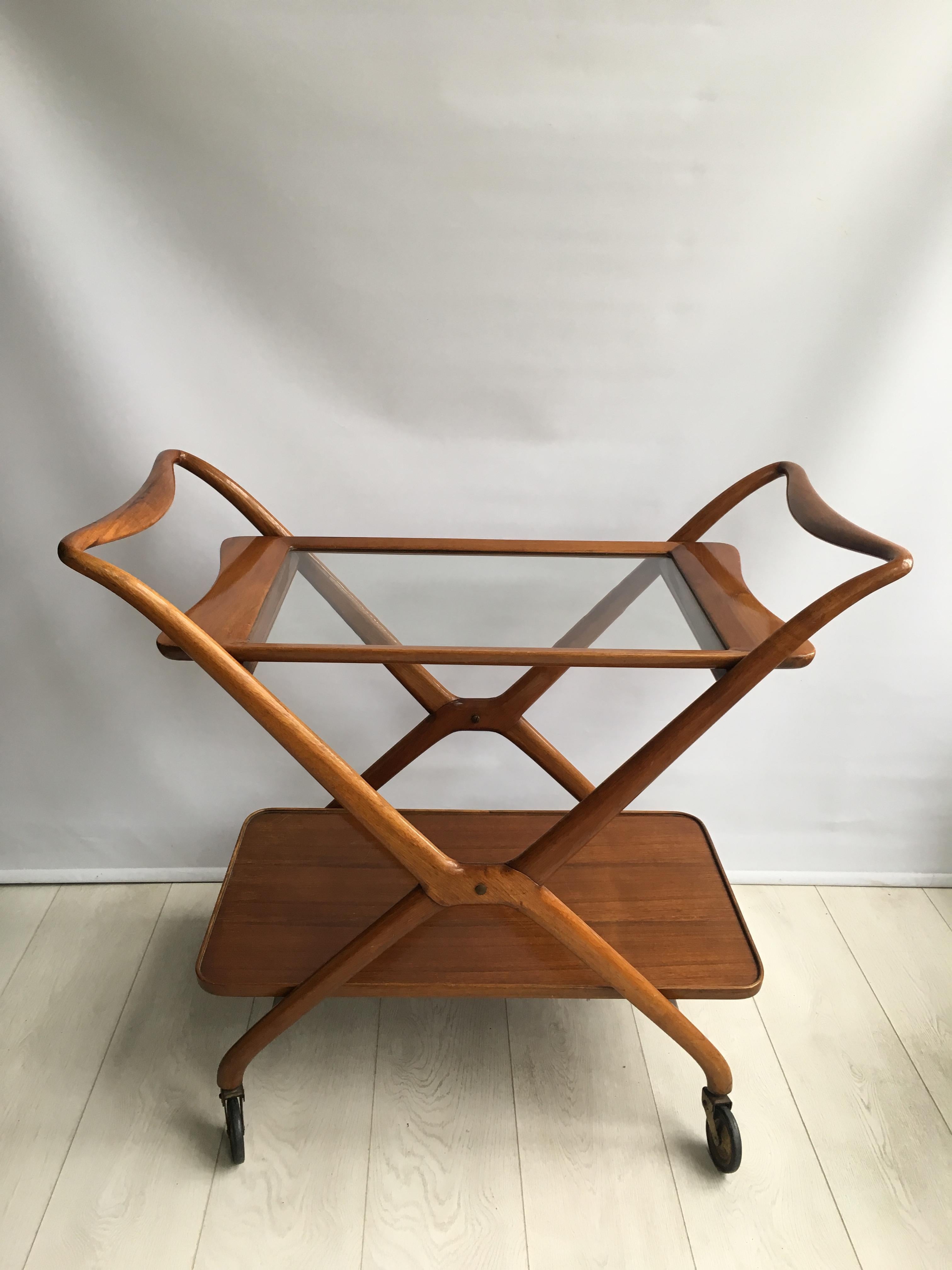 Great looking drinks trolley attributed to Ico Parisi for De Baggis

A smooth wooden cross-shaped frame with tapered handles in the style of Ico Parisi 
 
The trays can be removed and the frame folded up.

Some scratches to the bottom shelf as