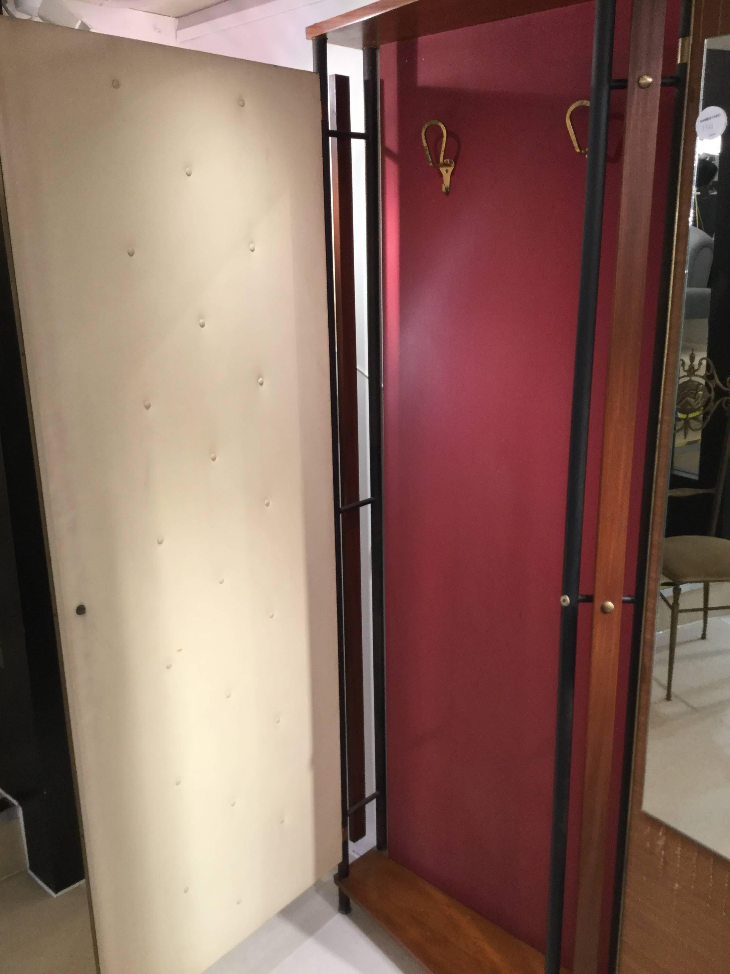 A very unique shallow entrance wardrobe manufactured by La Permanente Mobile Cantu' one door panel depicts a Tuscan landscape the other with a large mirror framed in palm-tree. The interior lined with elegant brass coat hangers.