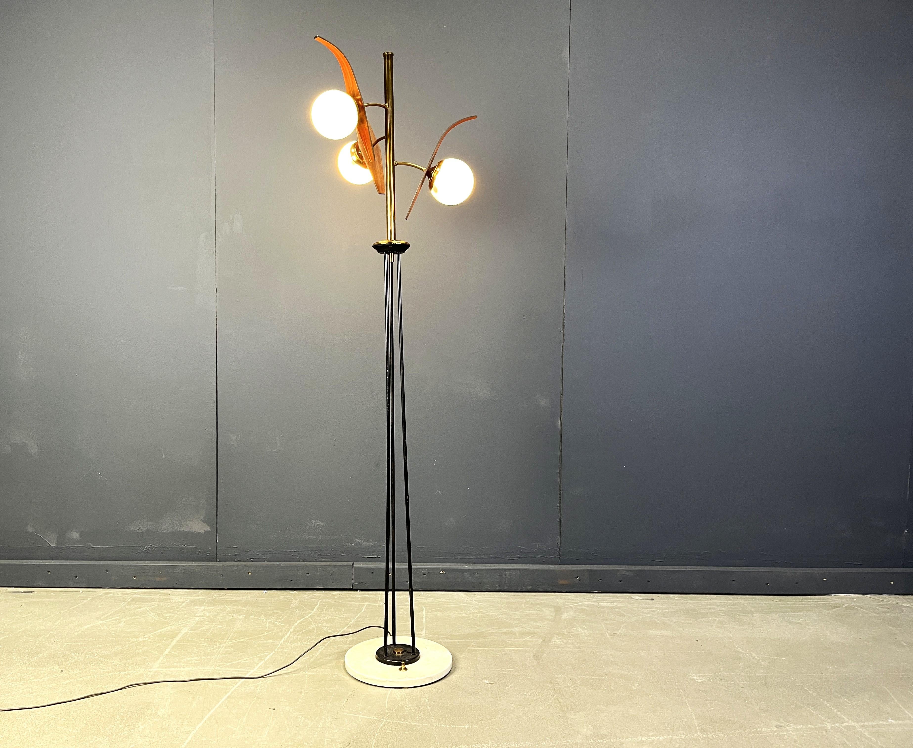 Mid century floor lamp with three milk glass globes, teak wooden reflectors and a black metal and brass brase.

The floor lamp has a white marble base with a nicely integrated brass switch. 

Because the way the switch is integrated in the marble