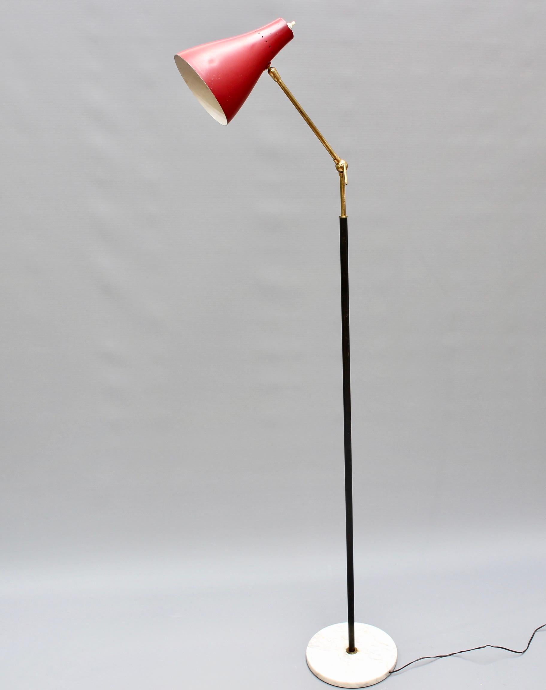 Midcentury Italian floor lamp from Stilnovo (circa 1950s). Italian design at its best, this is a floor lamp with adjustable angle for reading or spotlighting. The base of the lamp is a round of Carrara marble. The original red light cover is conical