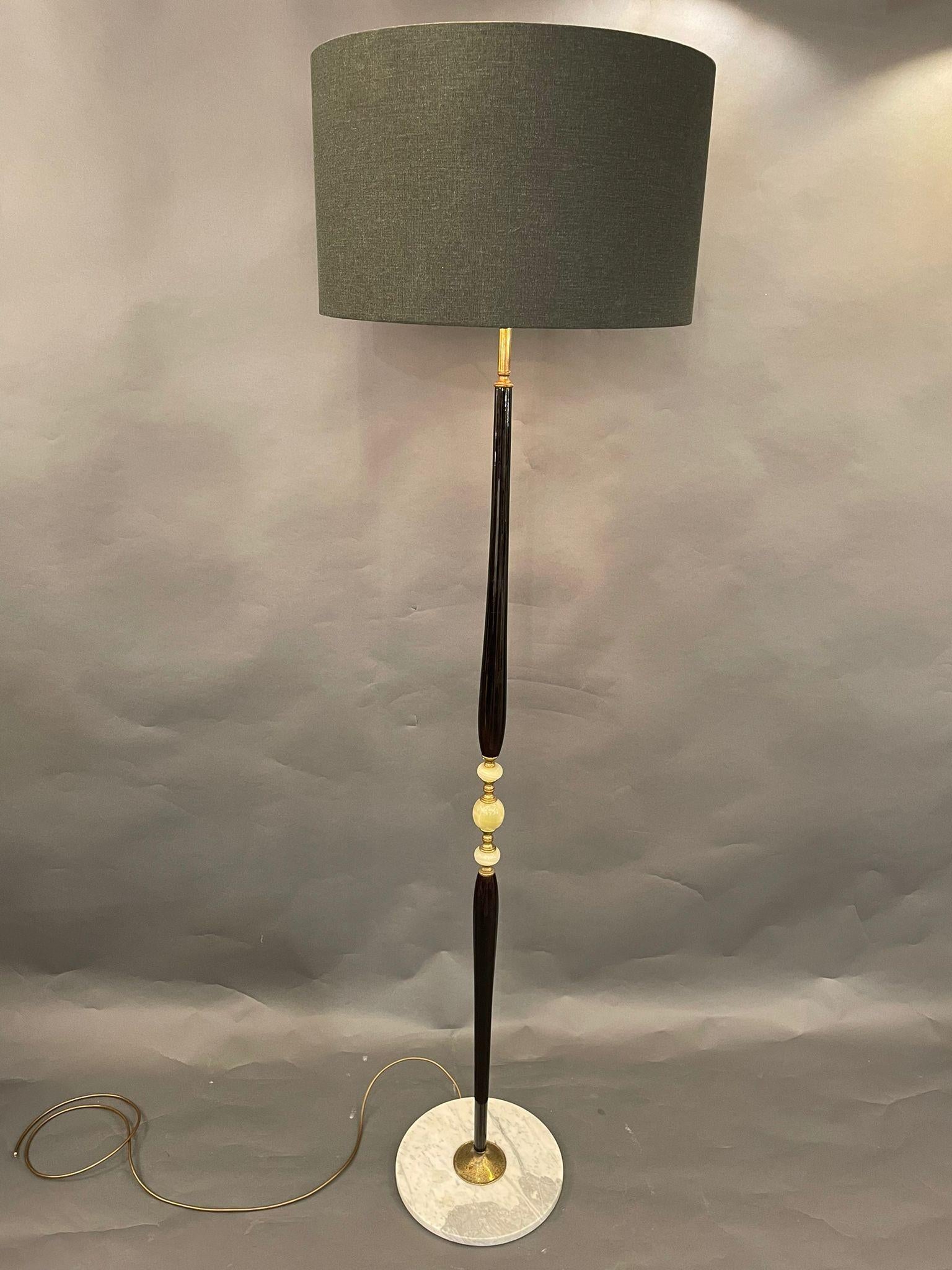 An elegant floor lamp in ebonized wood and onyx. The base is made of  Carrara marble. Italy 1950s.