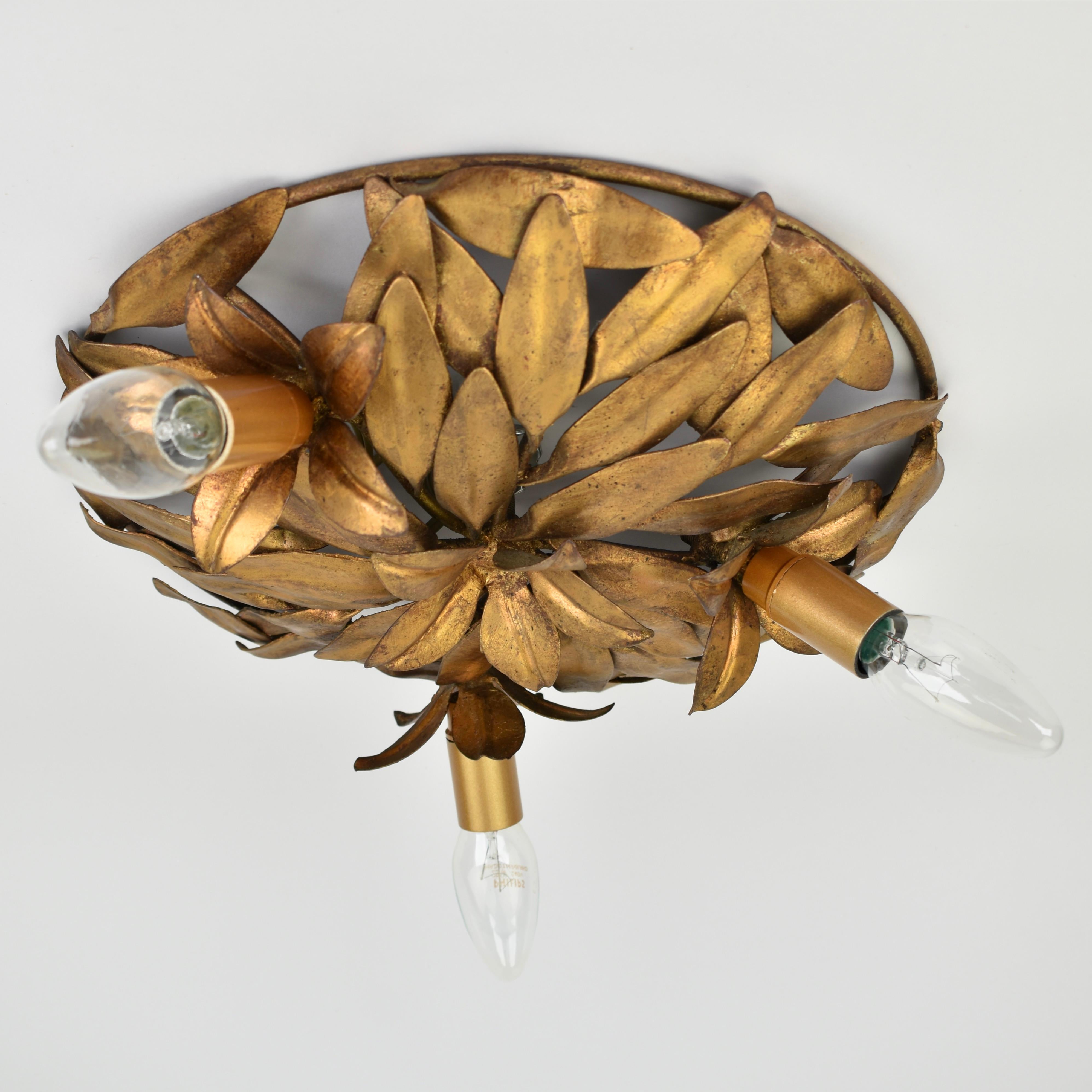Esta impresionante lámpara de techo italiana empotrada de los años 50 es una auténtica obra maestra, fabricada en hierro dorado con un elegante motivo floral y de hojas en el clásico estilo florentino.

La luminaria dispone de tres puntos de luz,