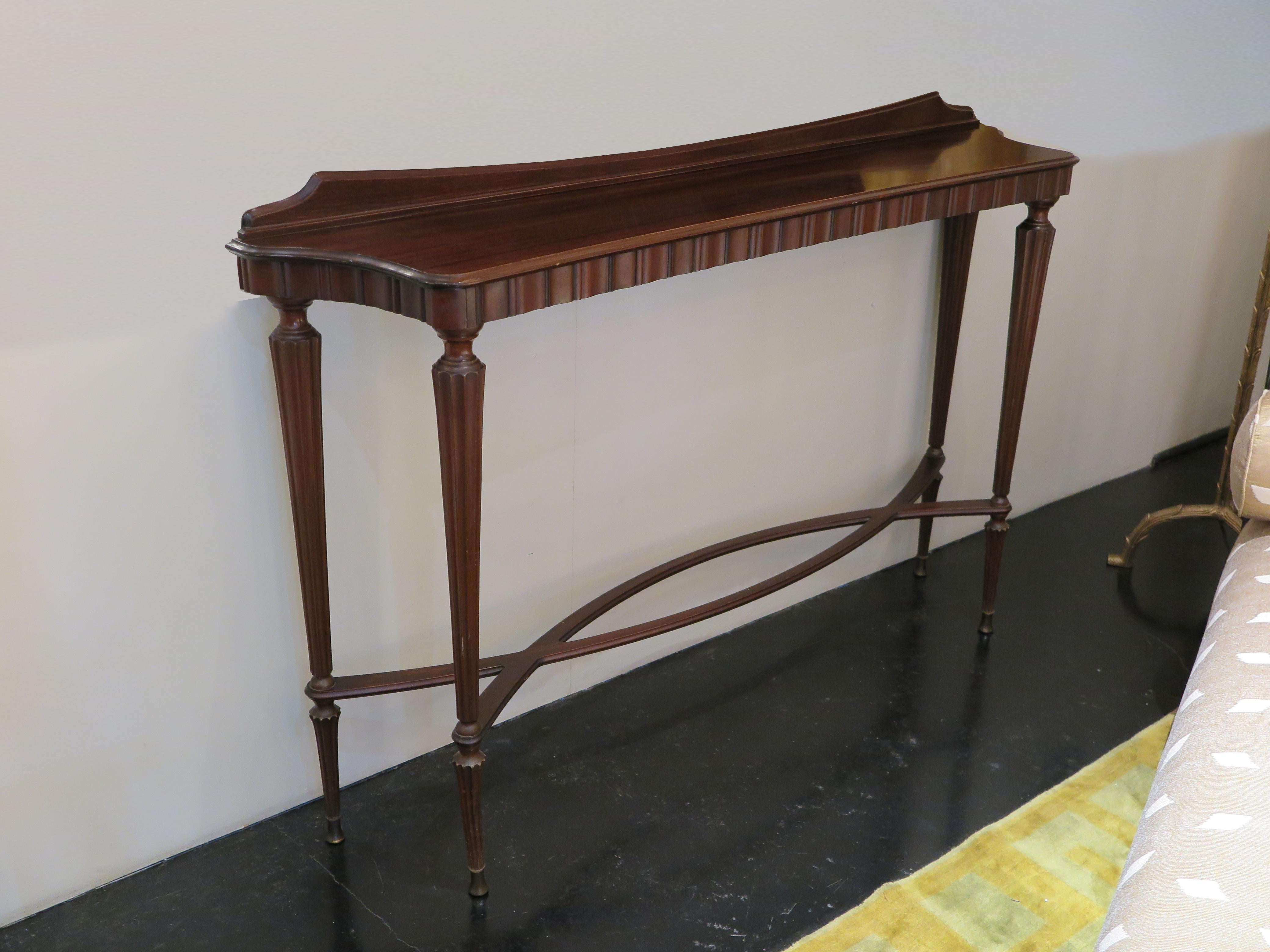 Italian Mid-Century console in mahogany with beautiful fluted detailing along facade and sides. Four ribbed tapered legs support the delicate frame. The original brass hardware adds the finishing touch. The back plate along the top of the console is