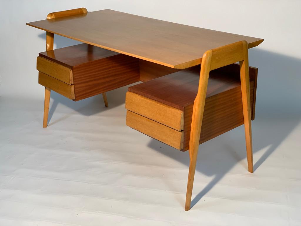 Italian writing desk from the 1950s with 4 drawers, two on the right and two on the left with overhanging open compartments, the contrast of the two wood colors enhances the shape of the desk.
Two fork-shaped supports positioned on the sides