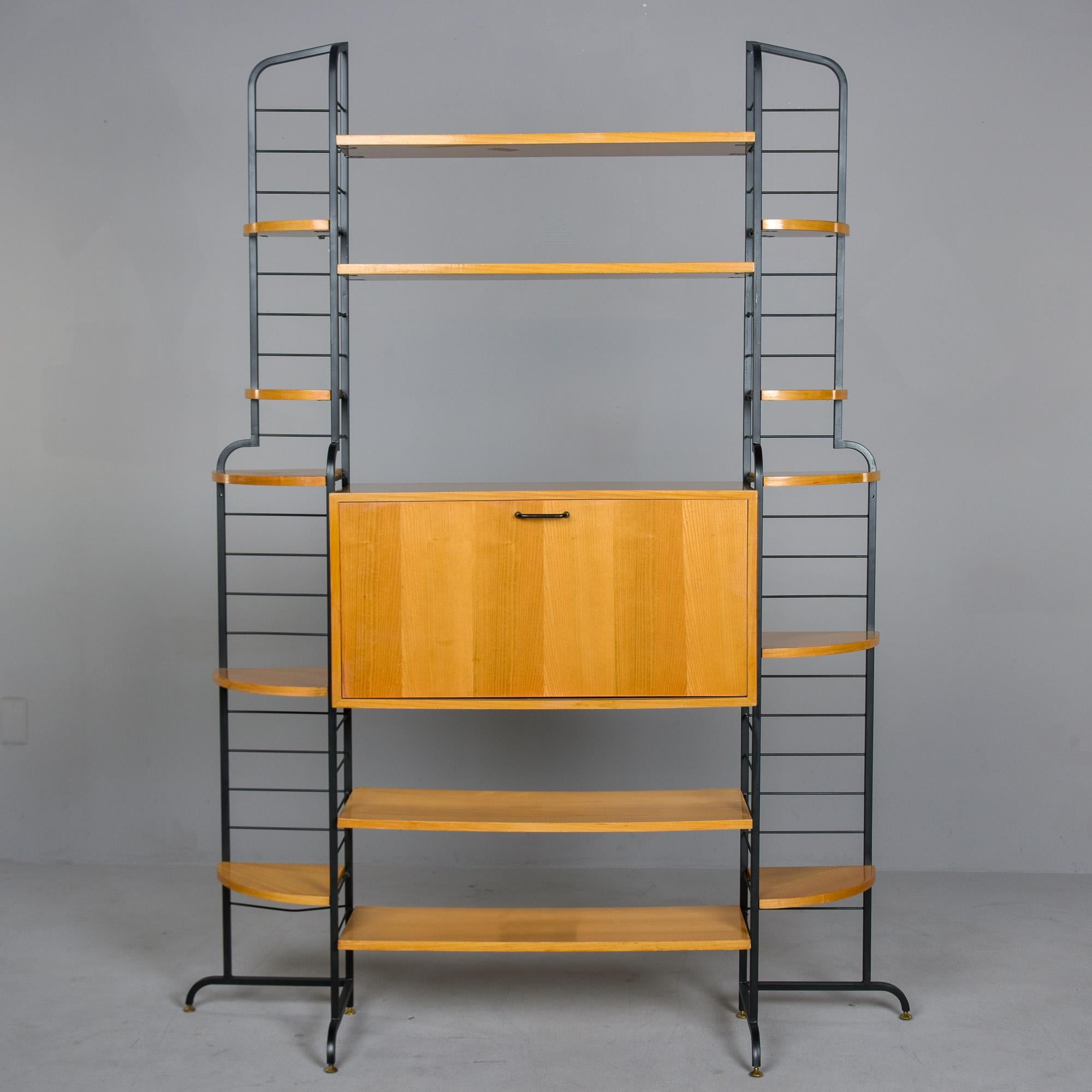 Encontrado en Italia, este mueble vintage de estantería independiente data de finales de los años 50/principios de los 60. La estructura metálica negra soporta estantes esquineros en los laterales y un armario/escritorio central con puerta abatible