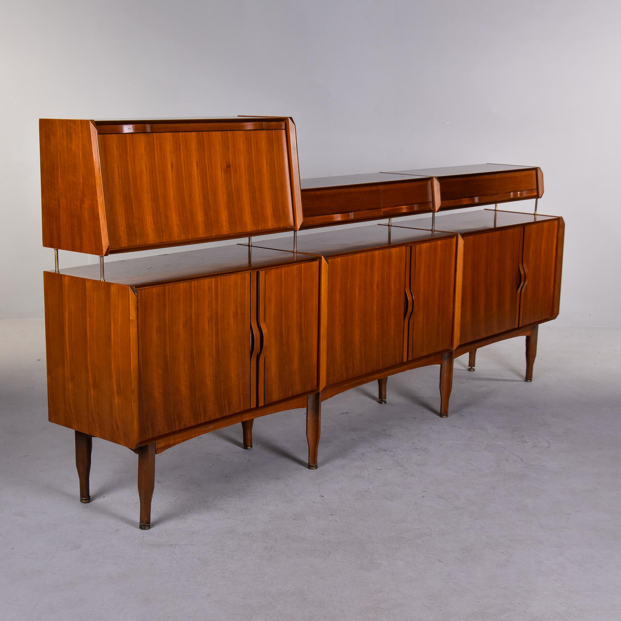 Found in Italy, this circa 1960s teak sideboard is attributed to Gianfranco Frattini. Unusual two tier design with the tallest section consisting of a cabinet with a fold down door and single interior glass shelf. The lower part of the top tier