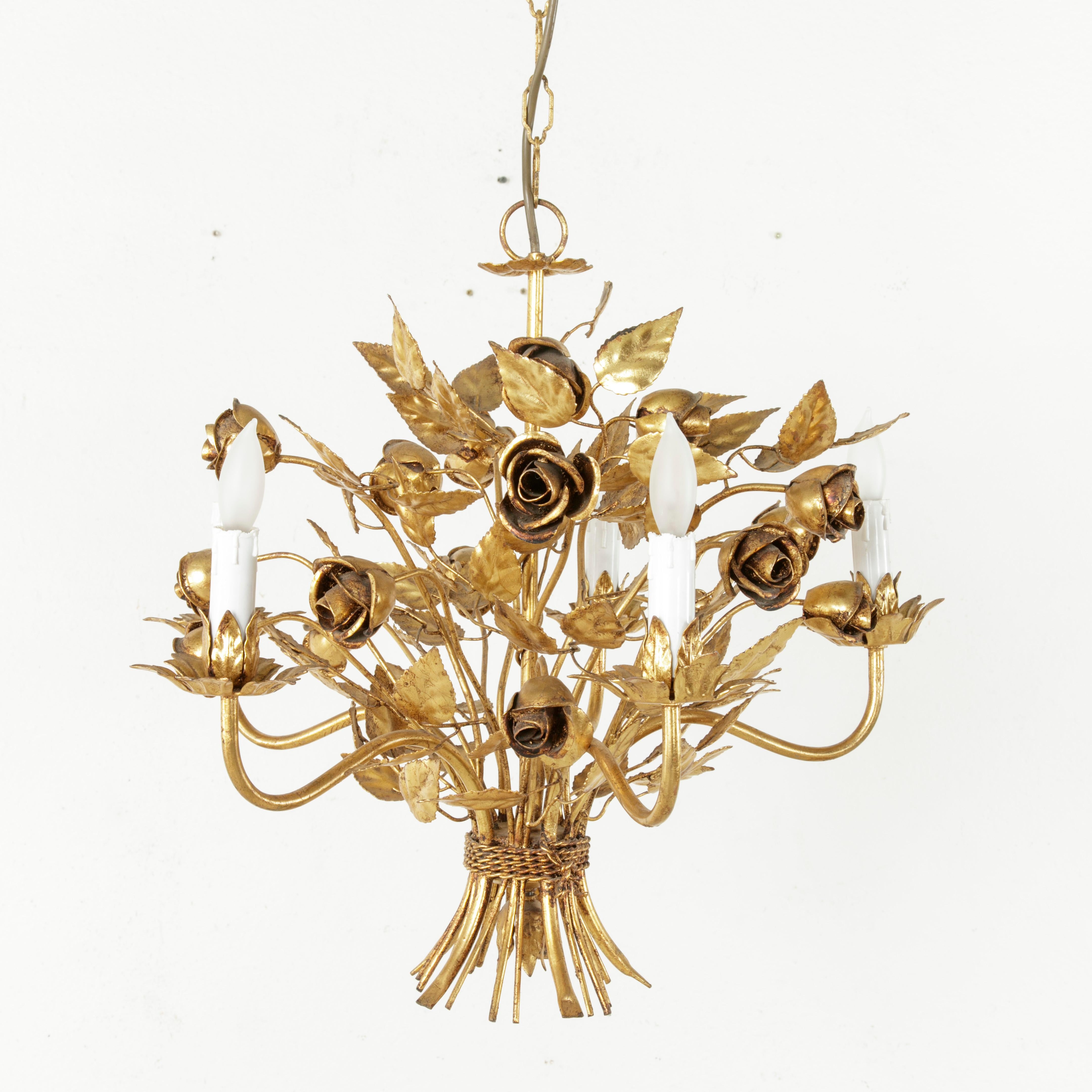 This midcentury Italian gilt metal chandelier with floral motif features a bouquet of roses and leaves bound with gilt metal twisted twine. Fitted with five lights and wired to American standards, it has its original gilt metal canopy. Its small