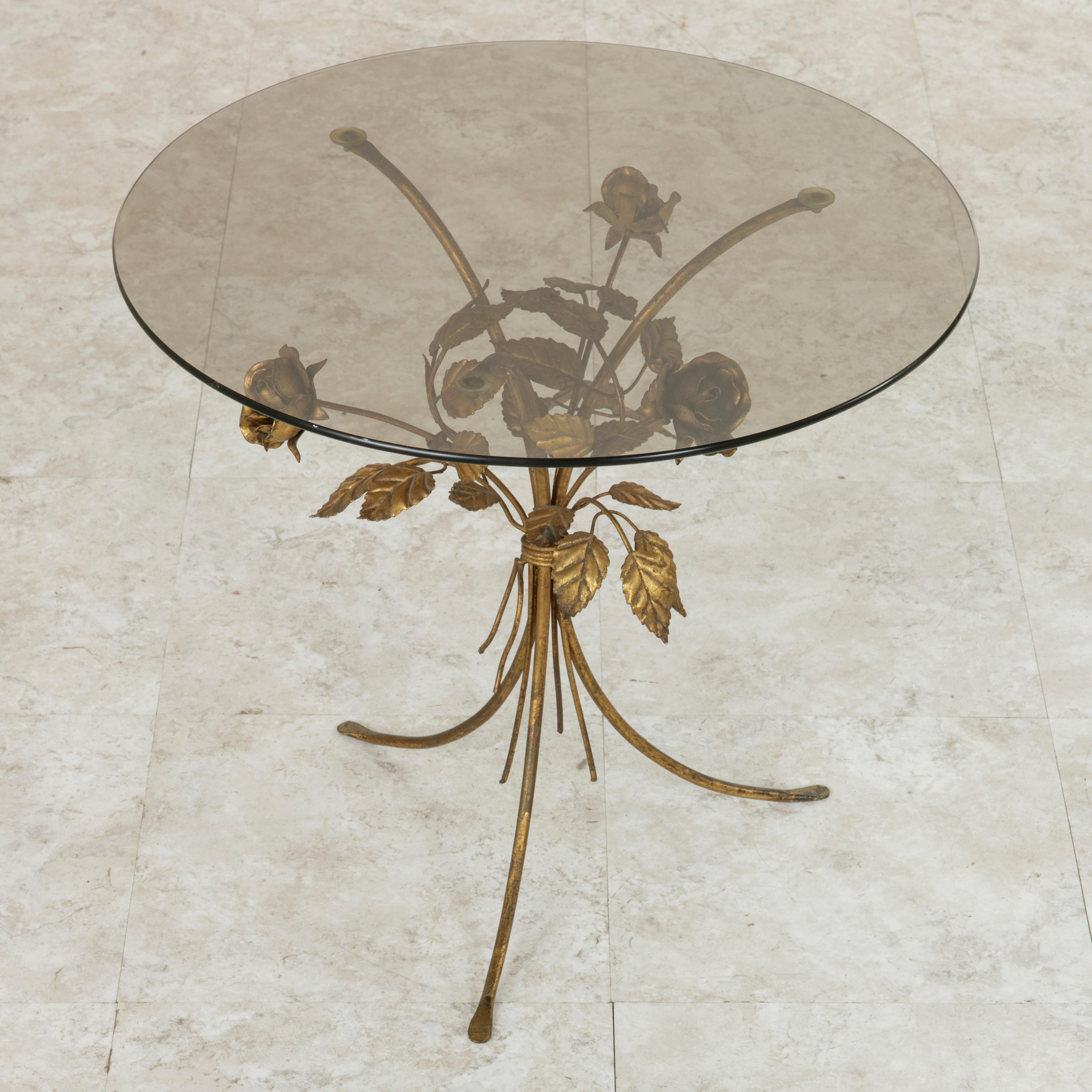This small scale midcentury Italian gilt metal side table features a bound bouquet of roses and leaves surrounding the three legs of its base. A round smoked glass top completes the look. With its 18-inch height and 20-inch diameter, this piece