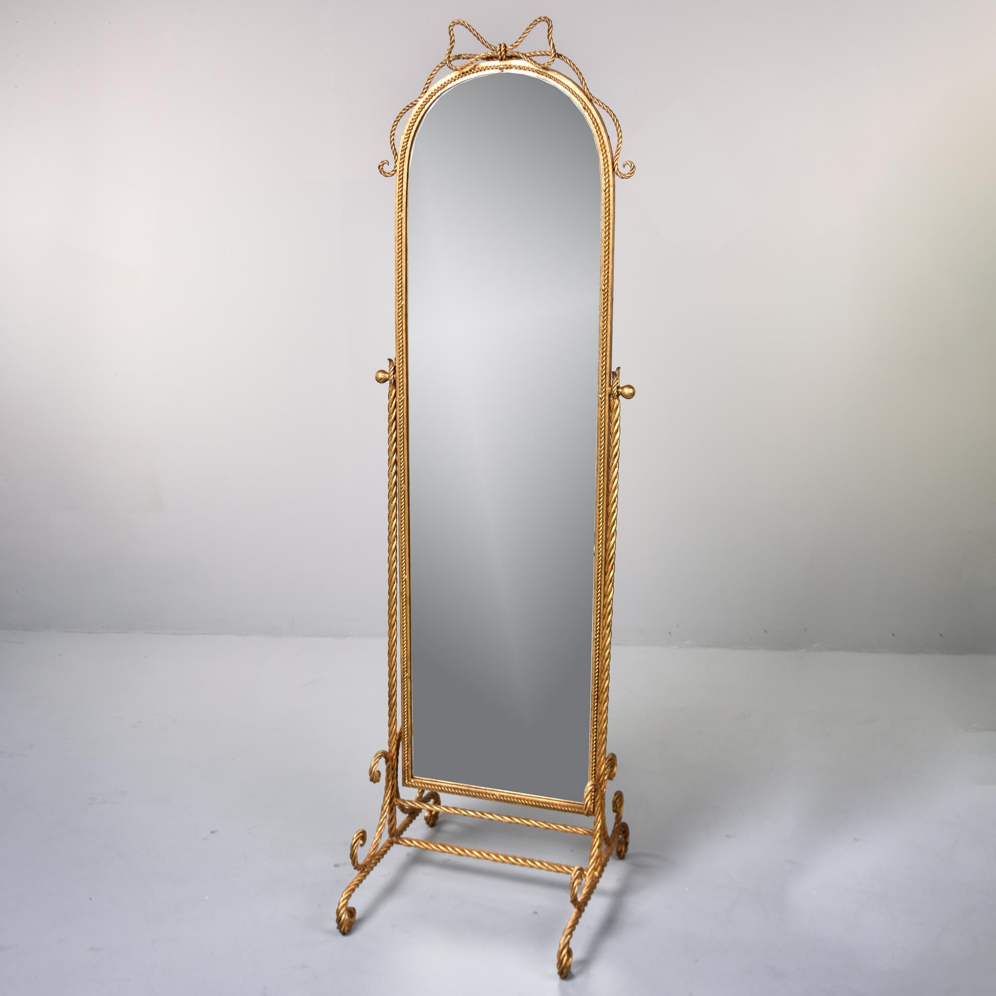 This Italian chevalier or standing mirror dates from the 1960s. Gilded metal frame features a base of thick, twisted metal strands with the mirror fitted to the base that allows it to swing from front to back. Tall mirror with arched top and braided