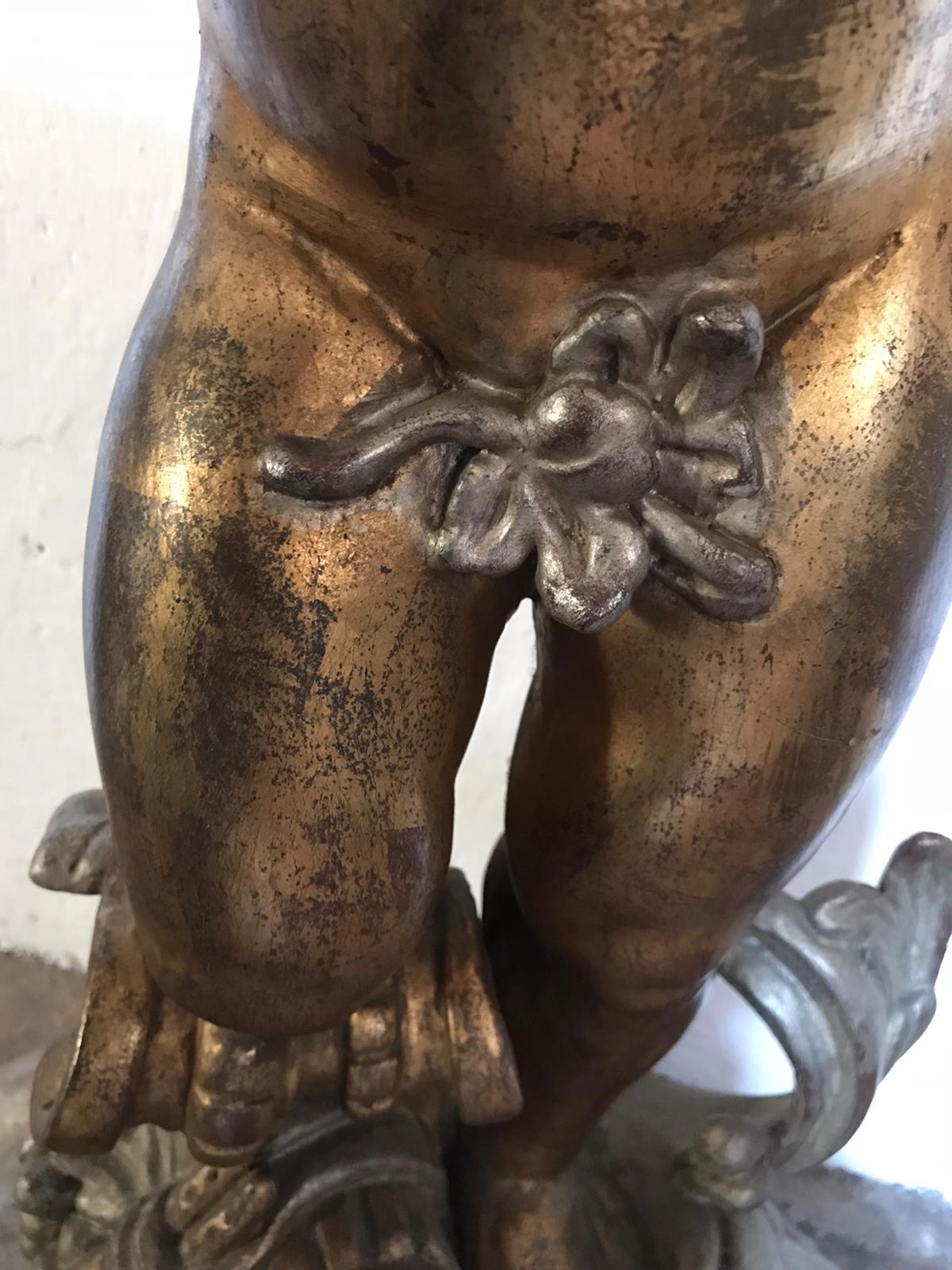 An exquisite Italian carved wood and gilt console table with a standing putto among grape vines and leaves with a decorated marble top.