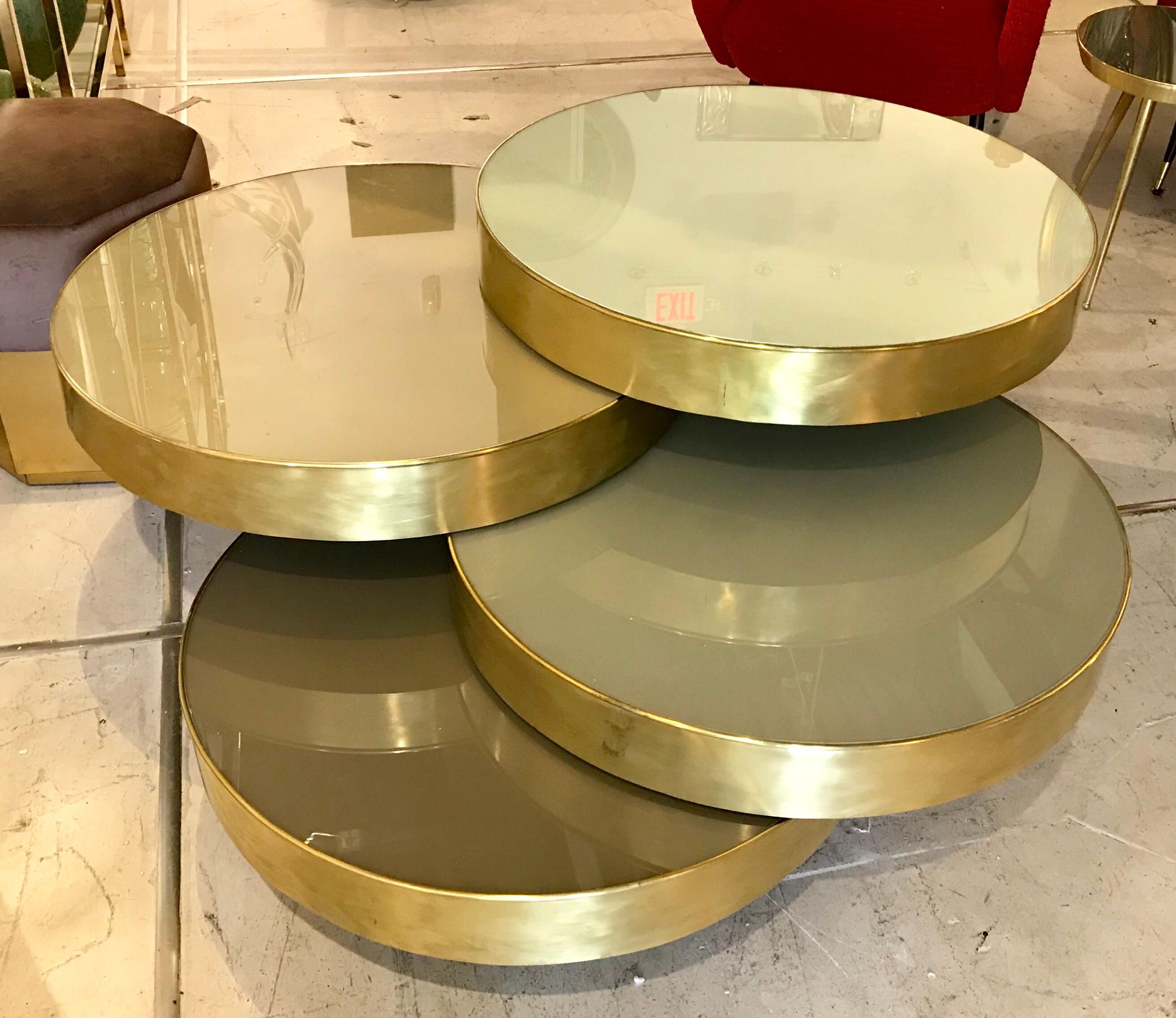Four layers of brass and glass roll open to form table tops at different heights and color tones.