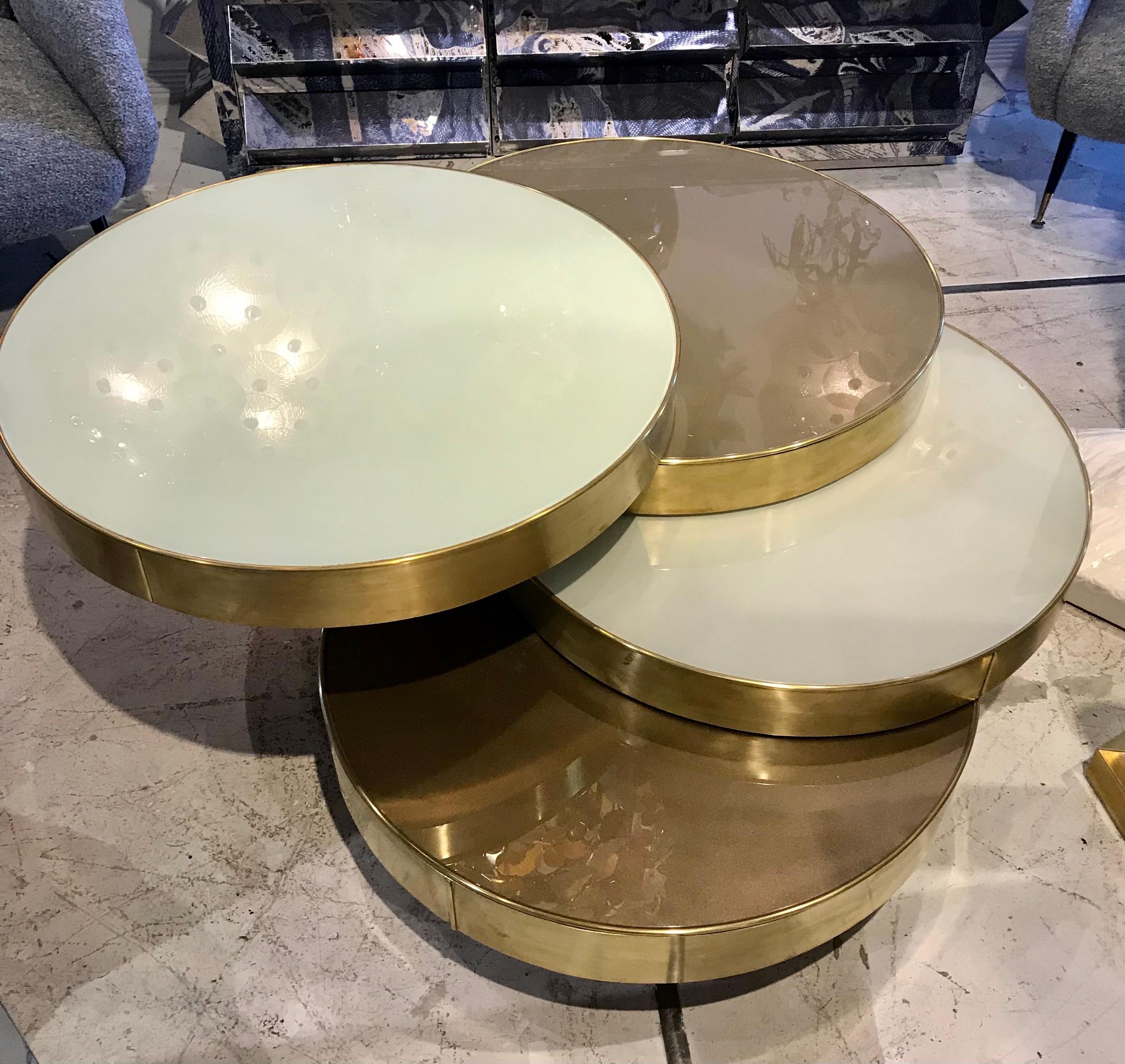 Four layers of reverse painted glass with brass trim roll open to form table tops at different heights and colors. The table fully opens to 60 inches.