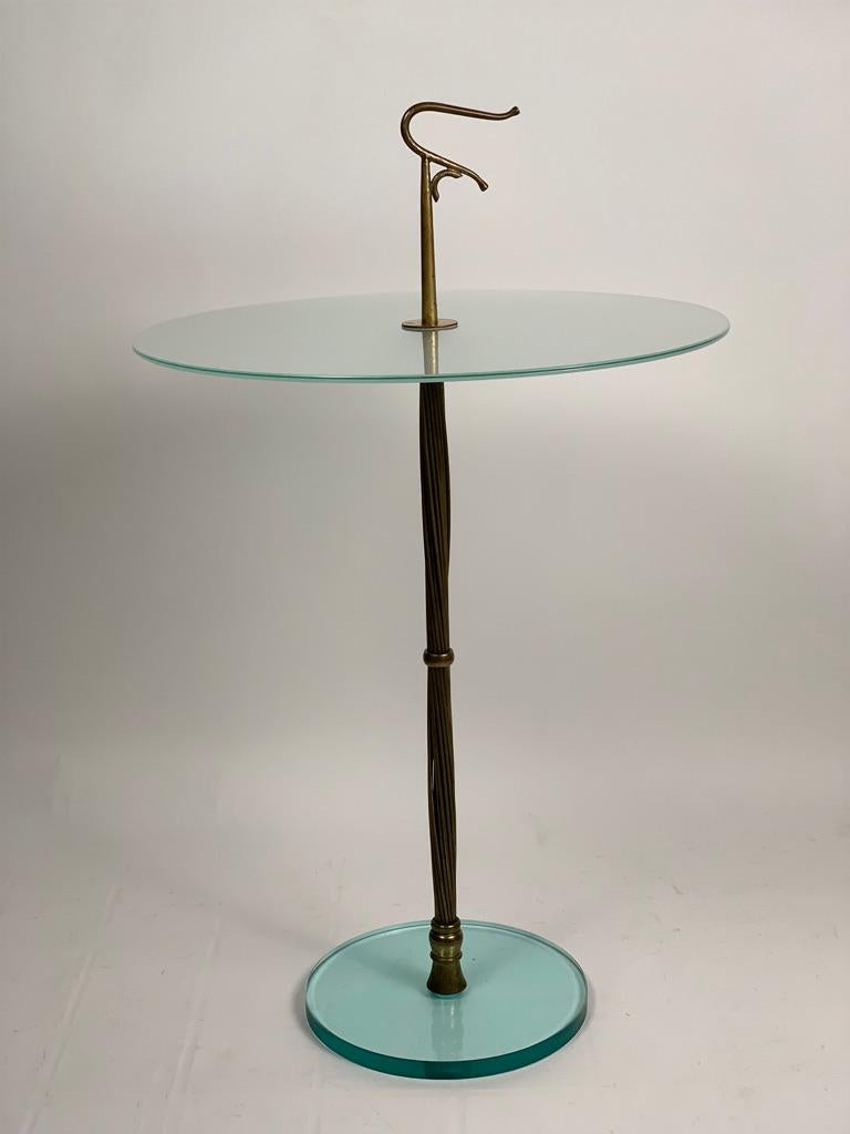 Italian serving table from the 50s with brass structure, the stem is made of twisted brass threads, ending at the apex with a handle to move the table easily.
 The base is a thick round ground glass, the larger top of the base always in ground