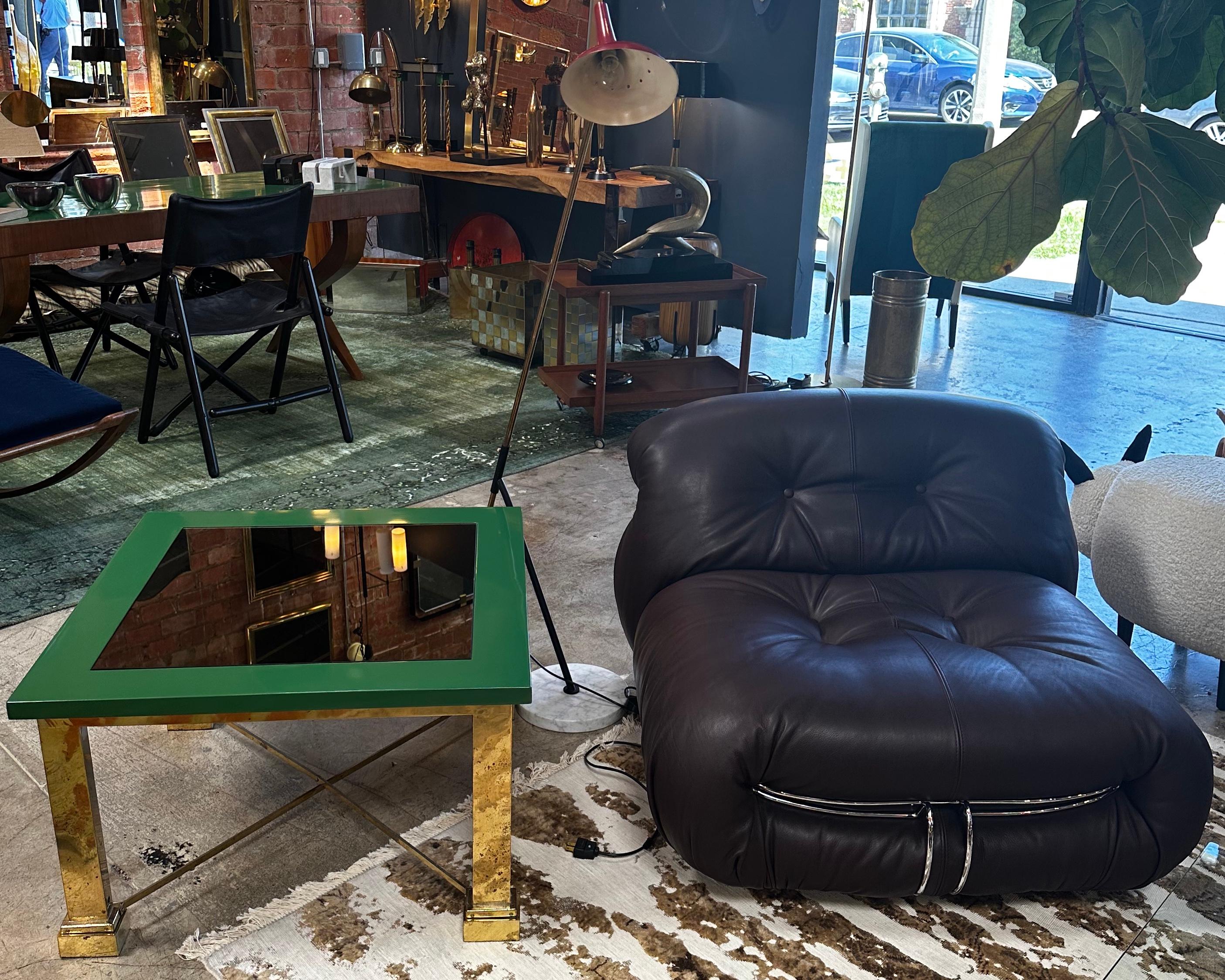 The midcentury Italian square coffee table from the 1980s, designed by Sergio Bucci, is a stunning piece that embodies the essence of the era. It boasts a fully brass base, providing both stability and a touch of opulence. The wood frame adds warmth