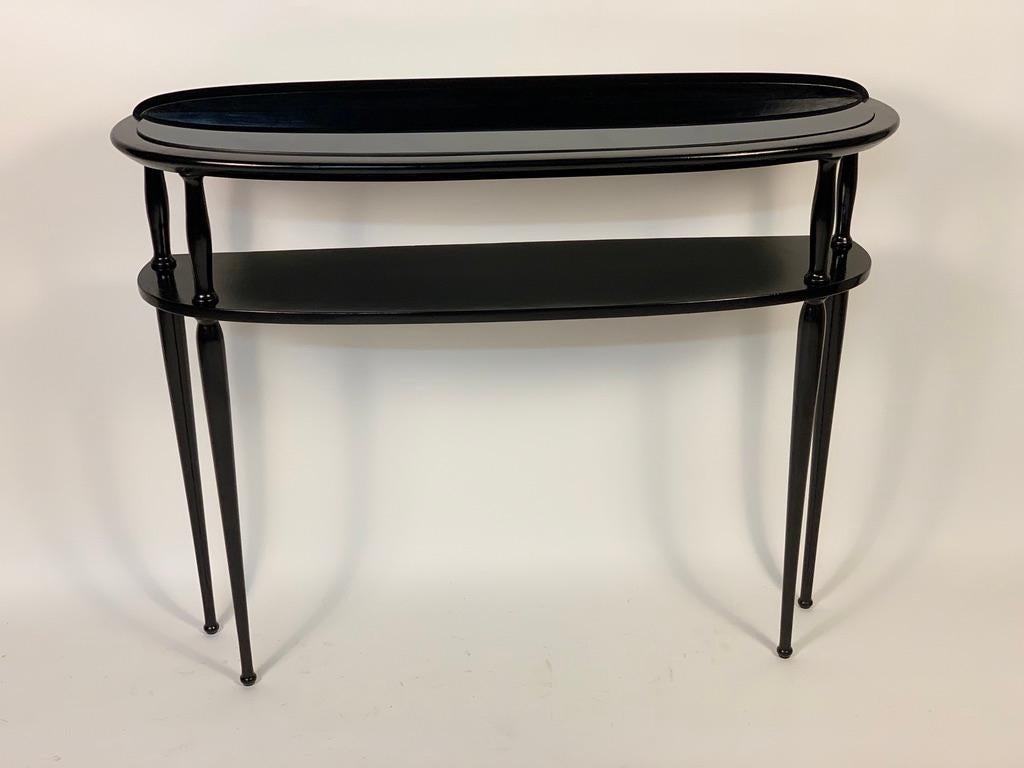 Half moon console, two shelves, the upper one with black glass embedded in the structure.
Four tapered legs.
Italy, 1950s.